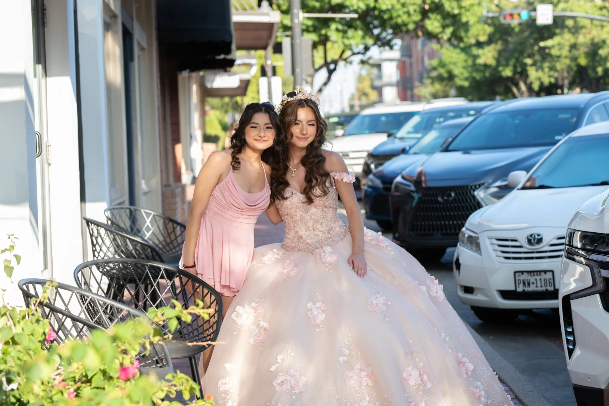 A sweet outdoor portrait as the quinceañera leans into her sister. The soft pink dresses, afternoon sunlight, and downtown backdrop give this moment a youthful editorial feel.