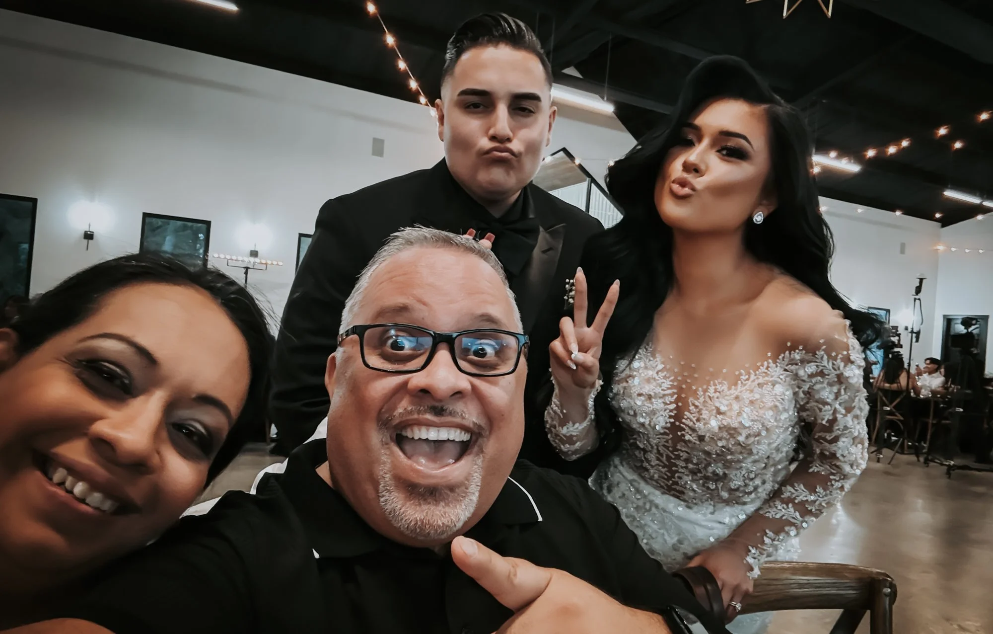 Photographer and team posing for a fun selfie with the bride and groom during a wedding reception.”