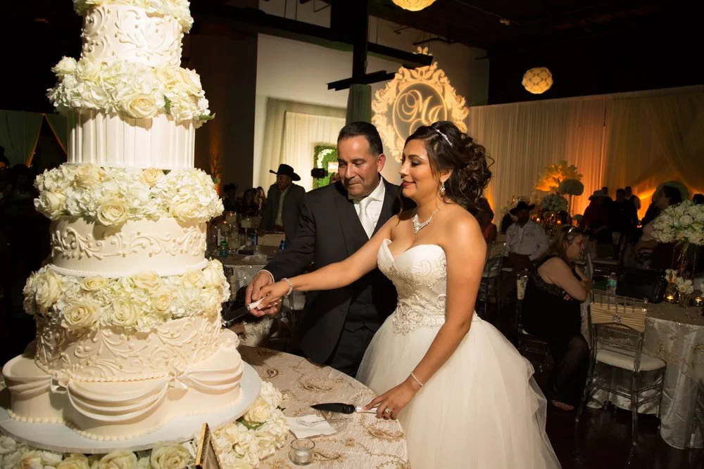 Bride and groom cutting a luxurious multi-tier wedding cake during their wedding reception celebration.