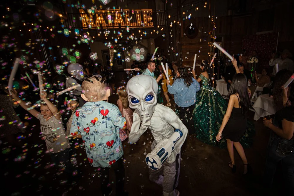 An exciting dance floor moment featuring bubbles, glowing lights, and a packed celebration as guests dance the night away. This image perfectly captures the fun, energy, and excitement of a modern Quinceañera reception.