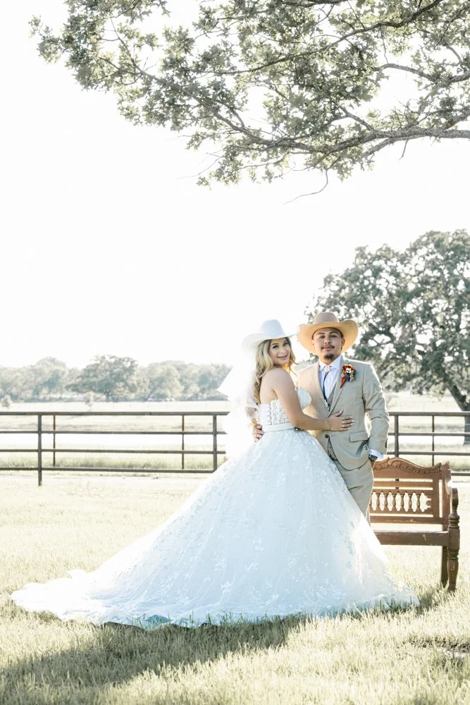 Ashley and Jerman pose together beneath a large Texas oak tree during their elegant western-inspired ranch wedding portrait session.
