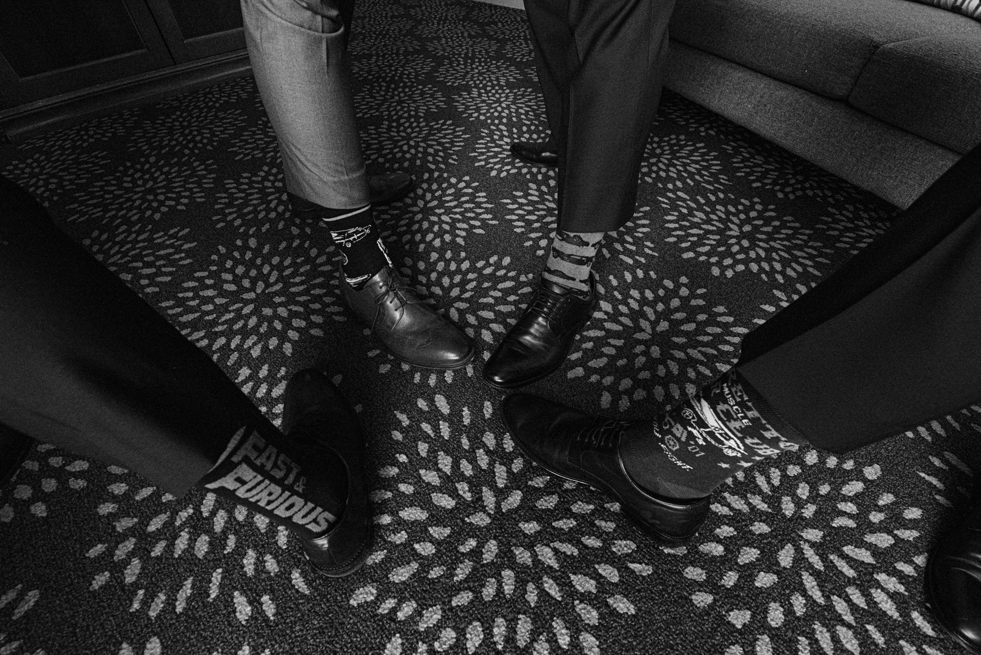 A creative detail shot of the groomsmen’s polished shoes and personalized socks, showcasing personality and camaraderie before the ceremony. This playful image adds a modern, storytelling element to the wedding day.