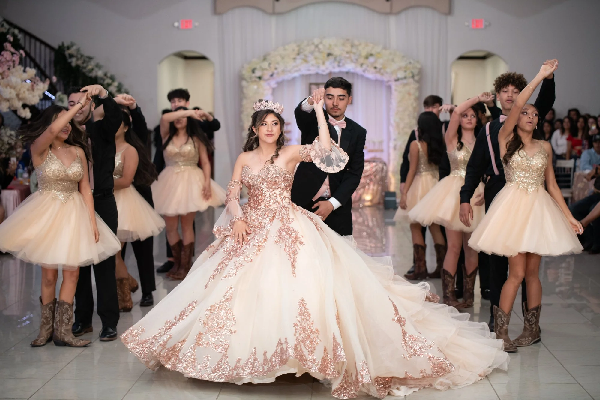 Katelyn glides across the dance floor in her rose gold ball gown surrounded by her damas and chambelanes dressed in coordinating champagne attire. The elegance of the choreography blends beautifully with the grandeur of her gown.