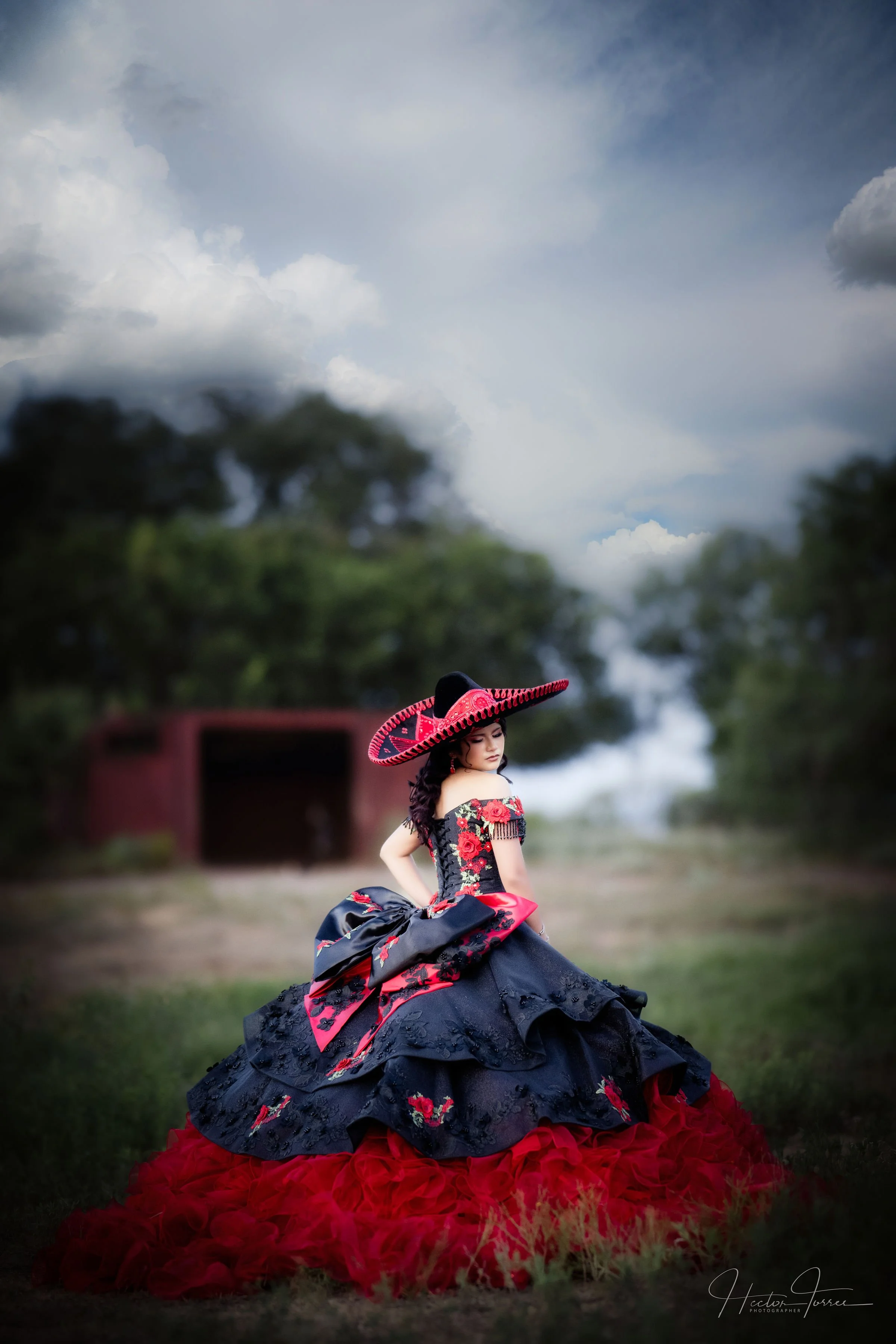 Quinceañera portrait wearing a traditional black and red dress outdoors.