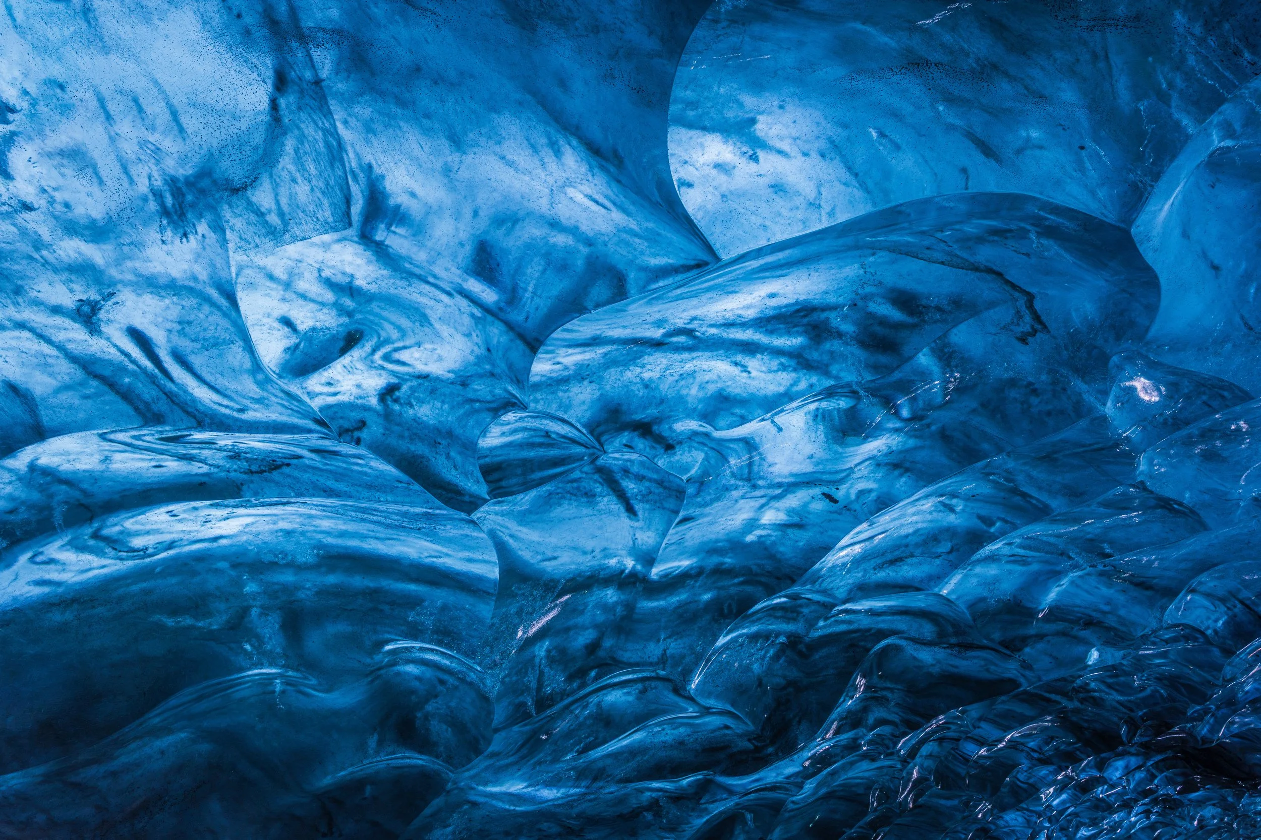 Close-up view of blue ice formations with smooth, glossy surfaces and textured patterns.
