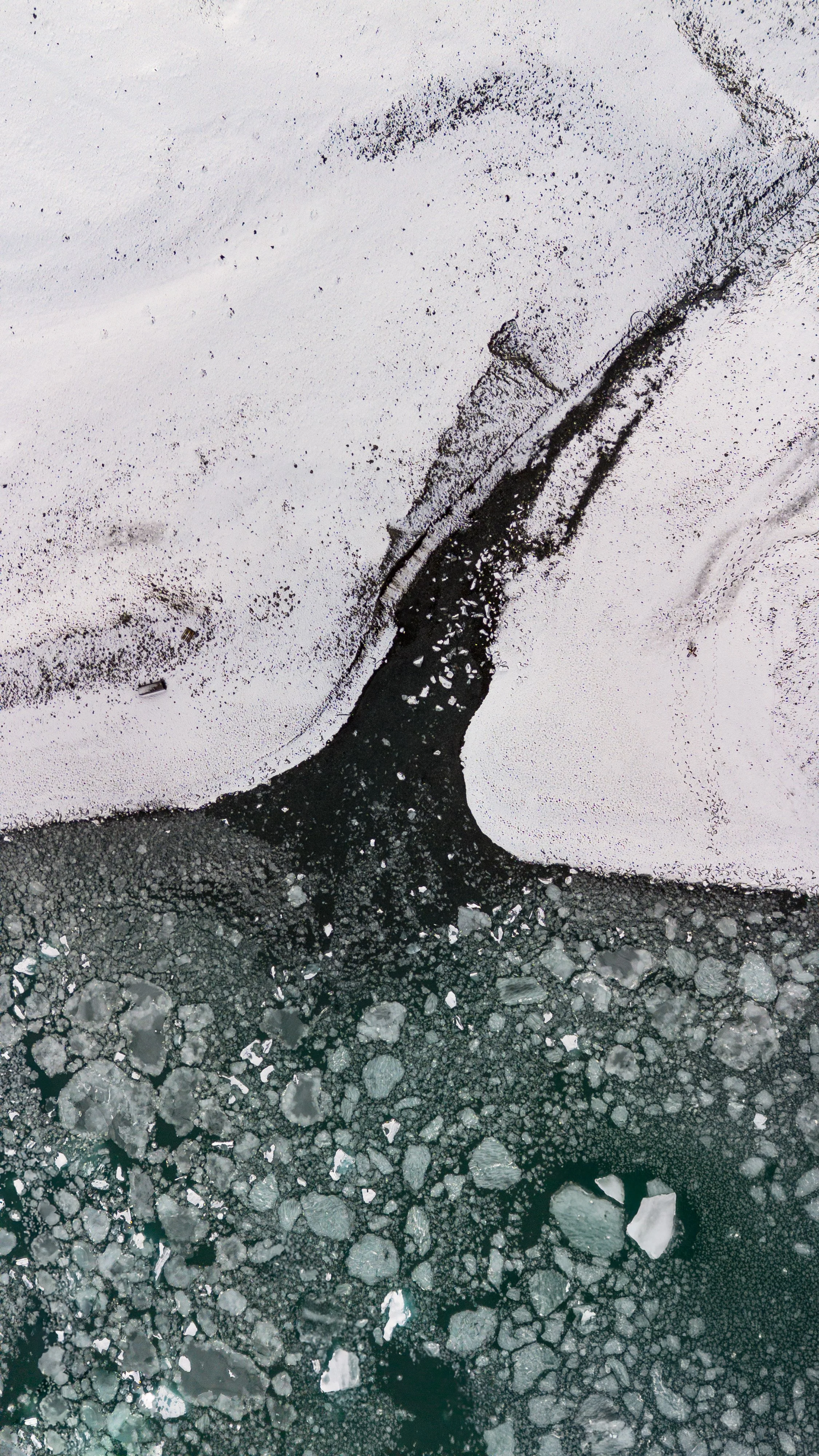 Aerial view of icy landscape with cracks in the ice and snow covering the surface.
