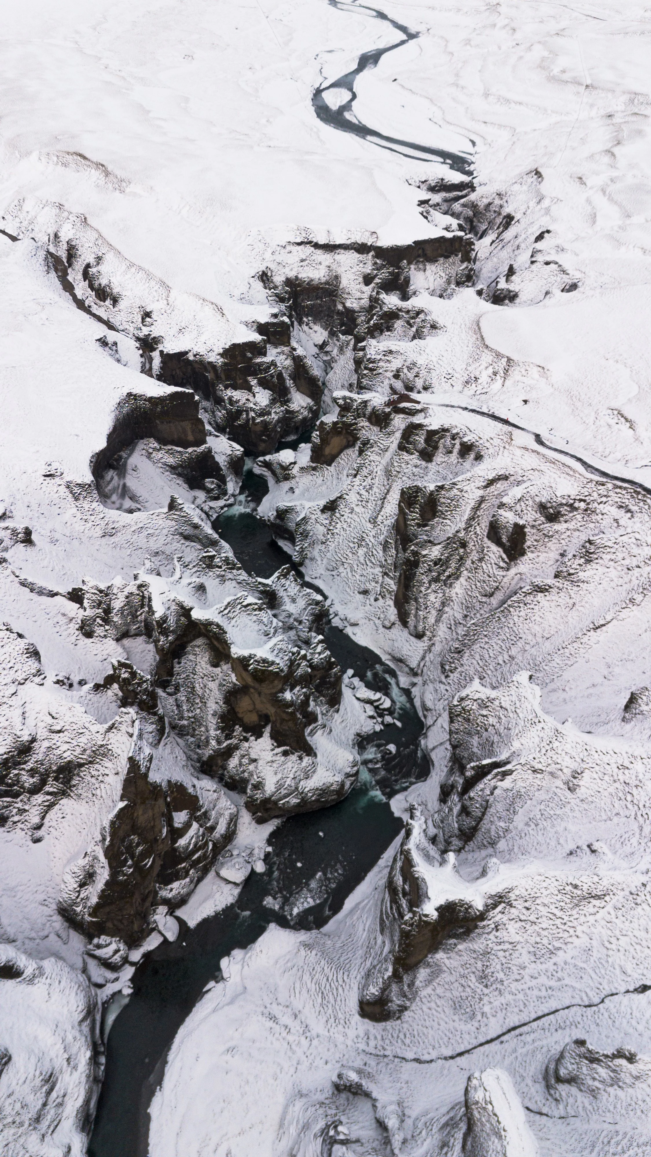 Aerial view of a snow-covered canyon with a river running through it.