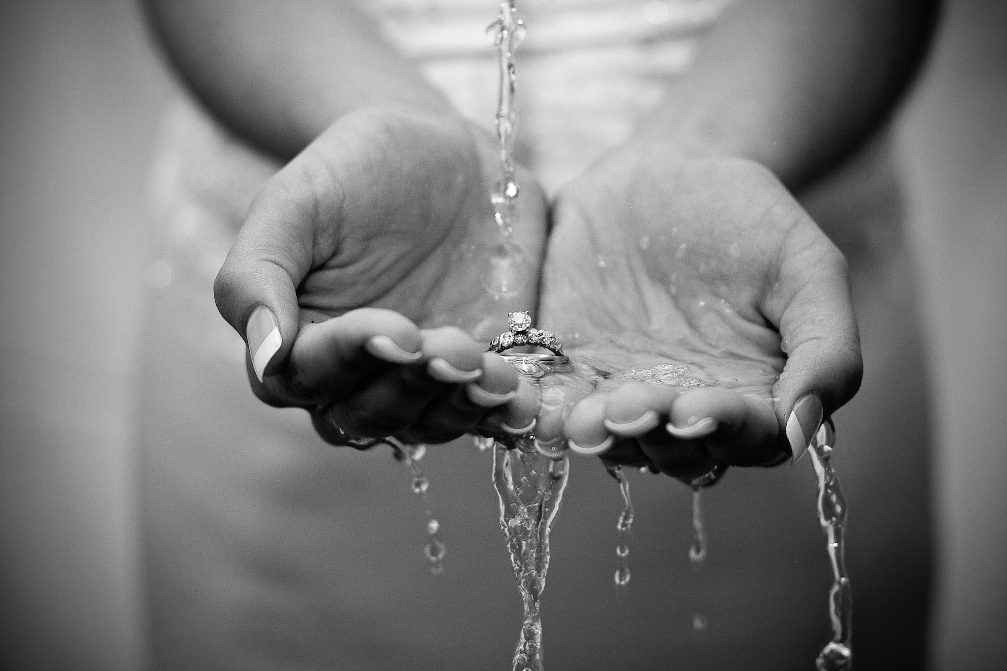 Creative wedding ring detail shot with water pouring over a bride’s hands, captured by Jeremiah Andrews, San Antonio Texas premier wedding photographer