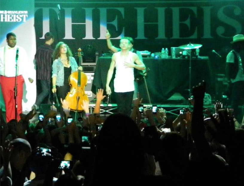 Cellist and hip-hop artist on stage performing in front of a crowd at a concert