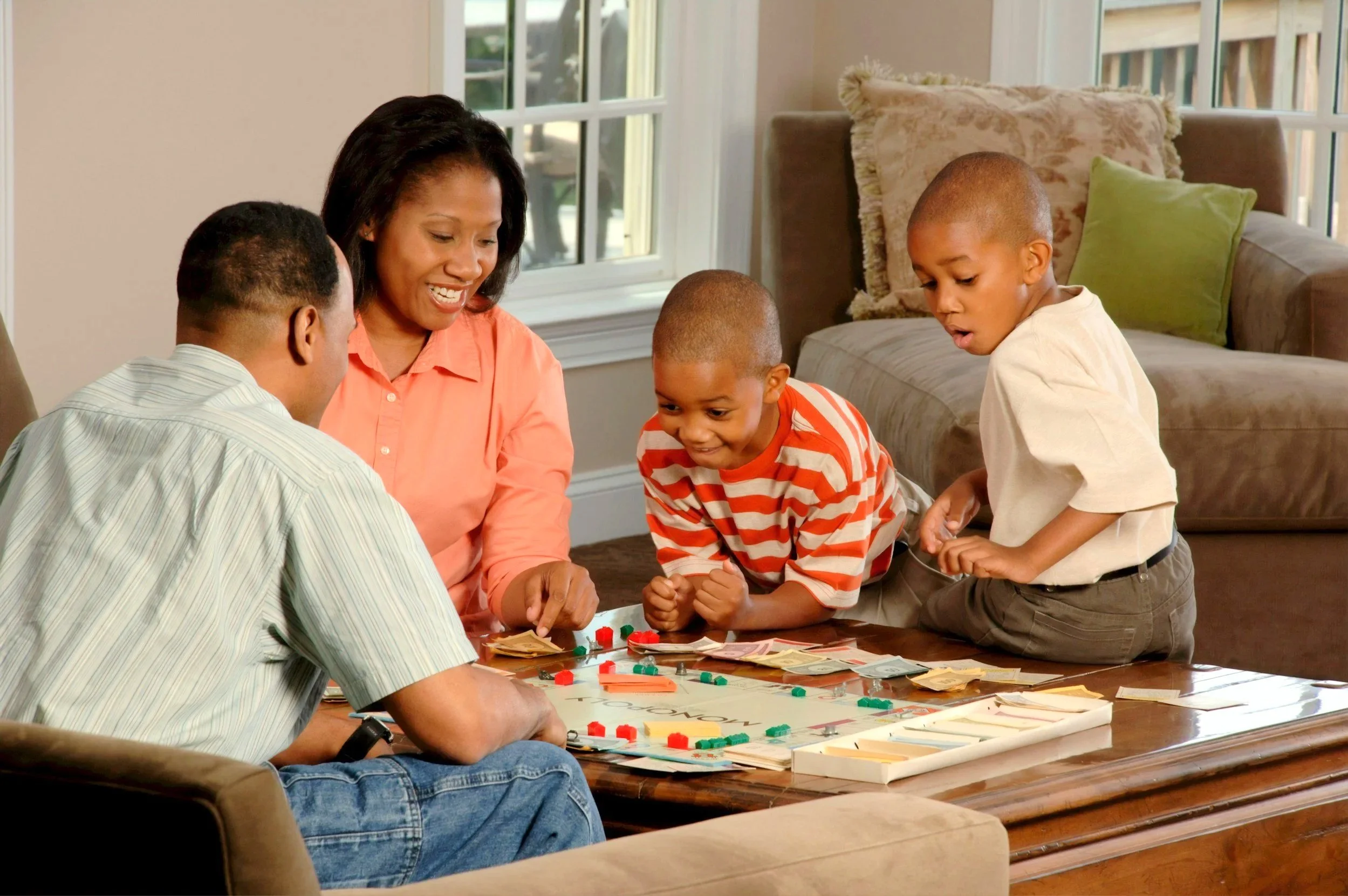 A family playing Monopoly game around a table in a living room.