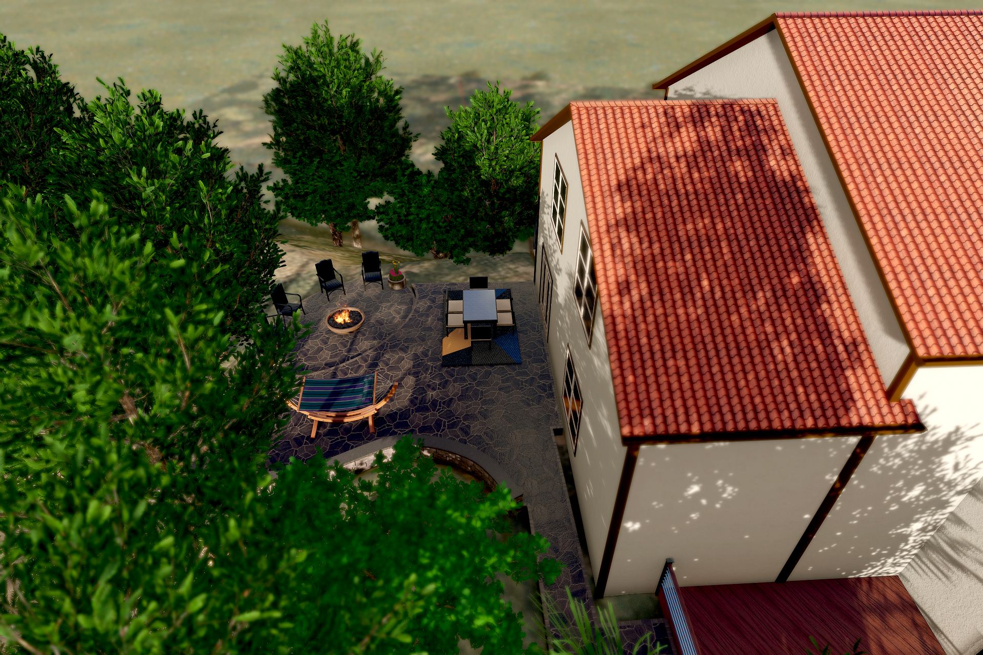 Aerial view of a backyard patio with outdoor furniture, a fire pit, a hammock, and trees surrounding a house with a red-tiled roof.