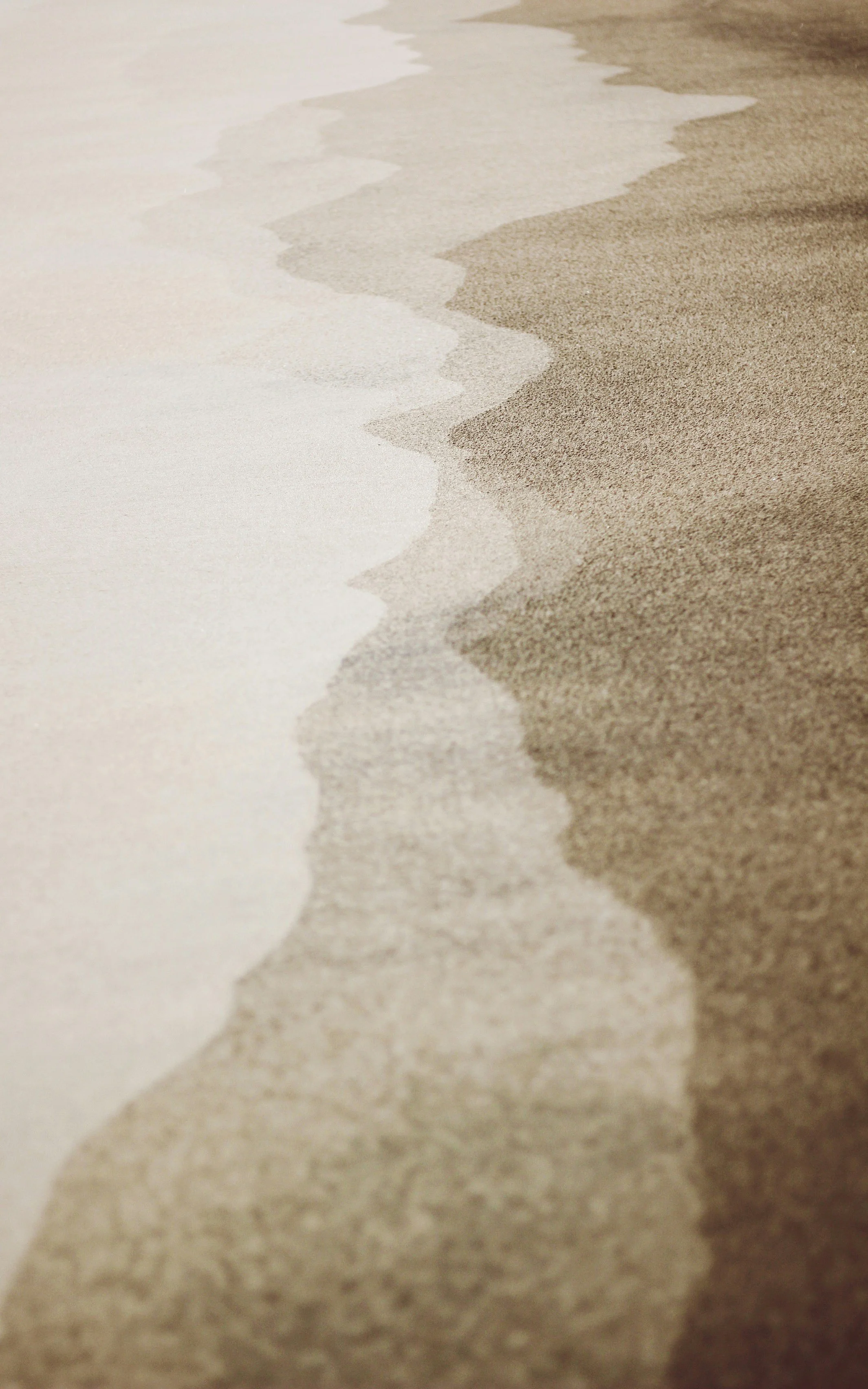 Close-up of a sandy beach with gentle waves washing onto the shore.