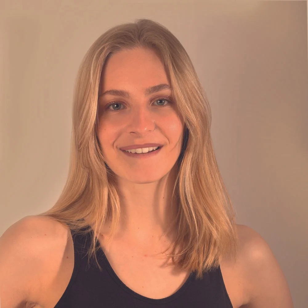 Mujer con cabello rubio, cabello liso y largo, sonriendo y usando una camiseta negra.