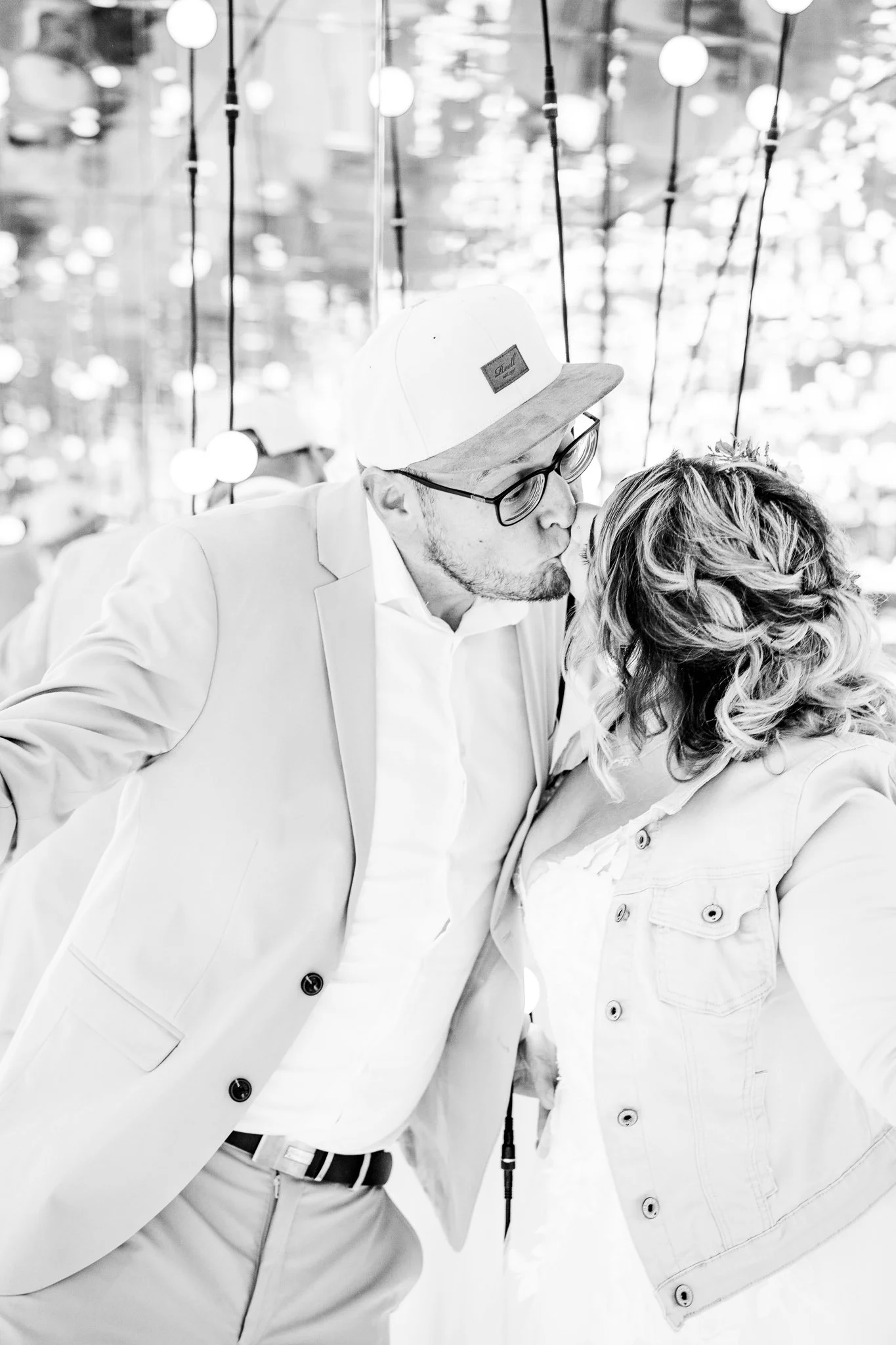 Laura und Sebastian küssen sich während ihrer Fotosession vor einer funkelnden Lichterdekoration