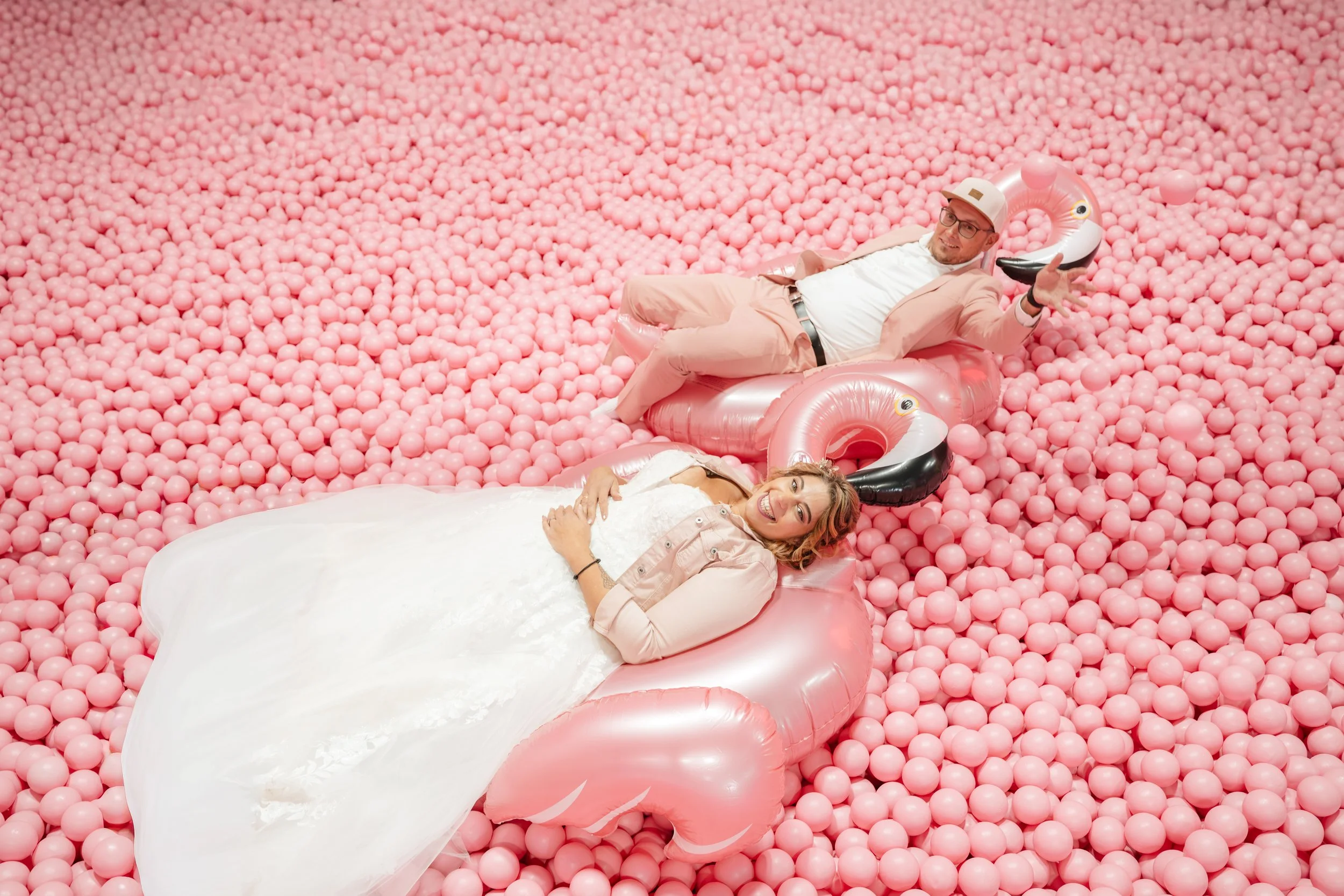 Kreatives Hochzeitsshooting im Supercandy Museum Köln – Braut und Bräutigam in pinker Ballgrube mit Flamingos, Hochzeitsfotograf und Videograf Köln