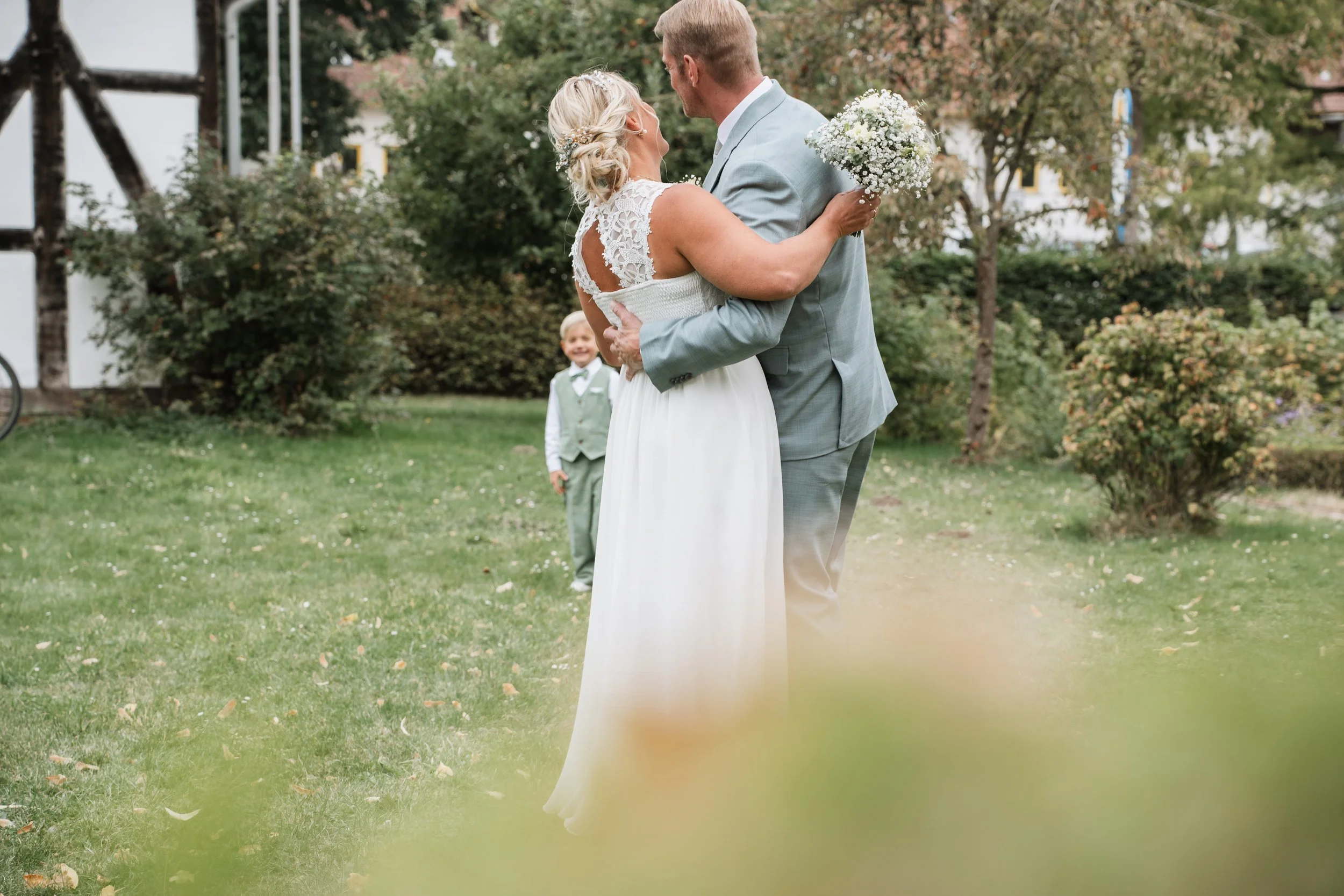 Brautpaar mit Kind im Garten – Hochzeitsfotografie & Videografie Museumsschule Hiddenhausen