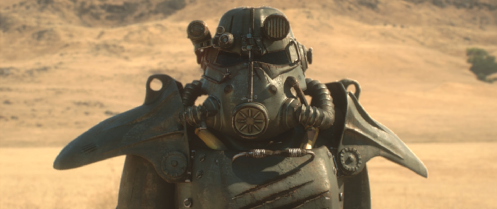 Close-up of a weathered armored helmet with hoses and mechanical attachments in a sunlit desert