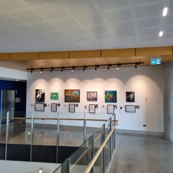 Art gallery wall displaying six paintings with informational plaques below each piece, in a modern museum setting.