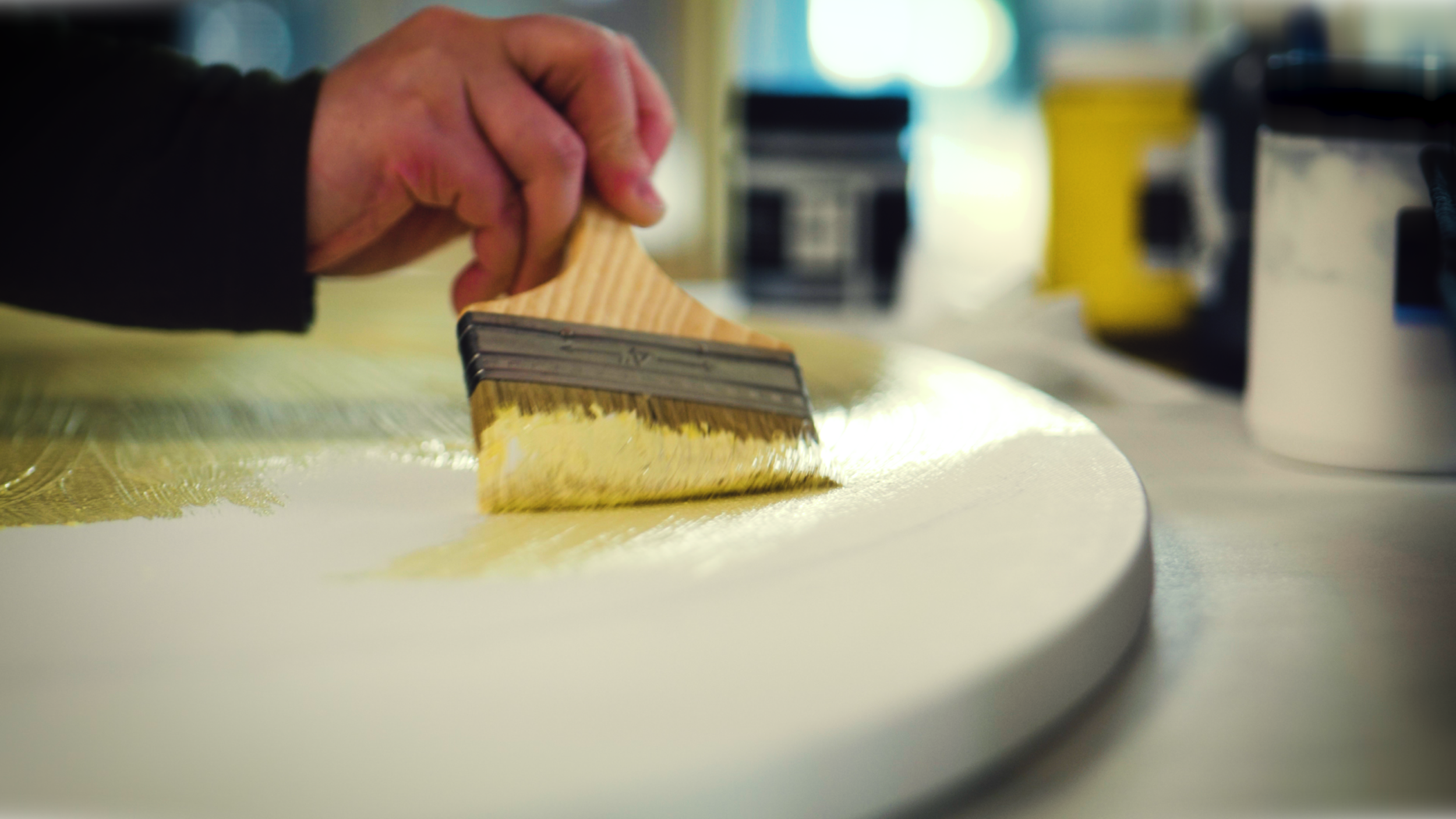 Close-up of a person applying gold leaf onto a surface with a brush.