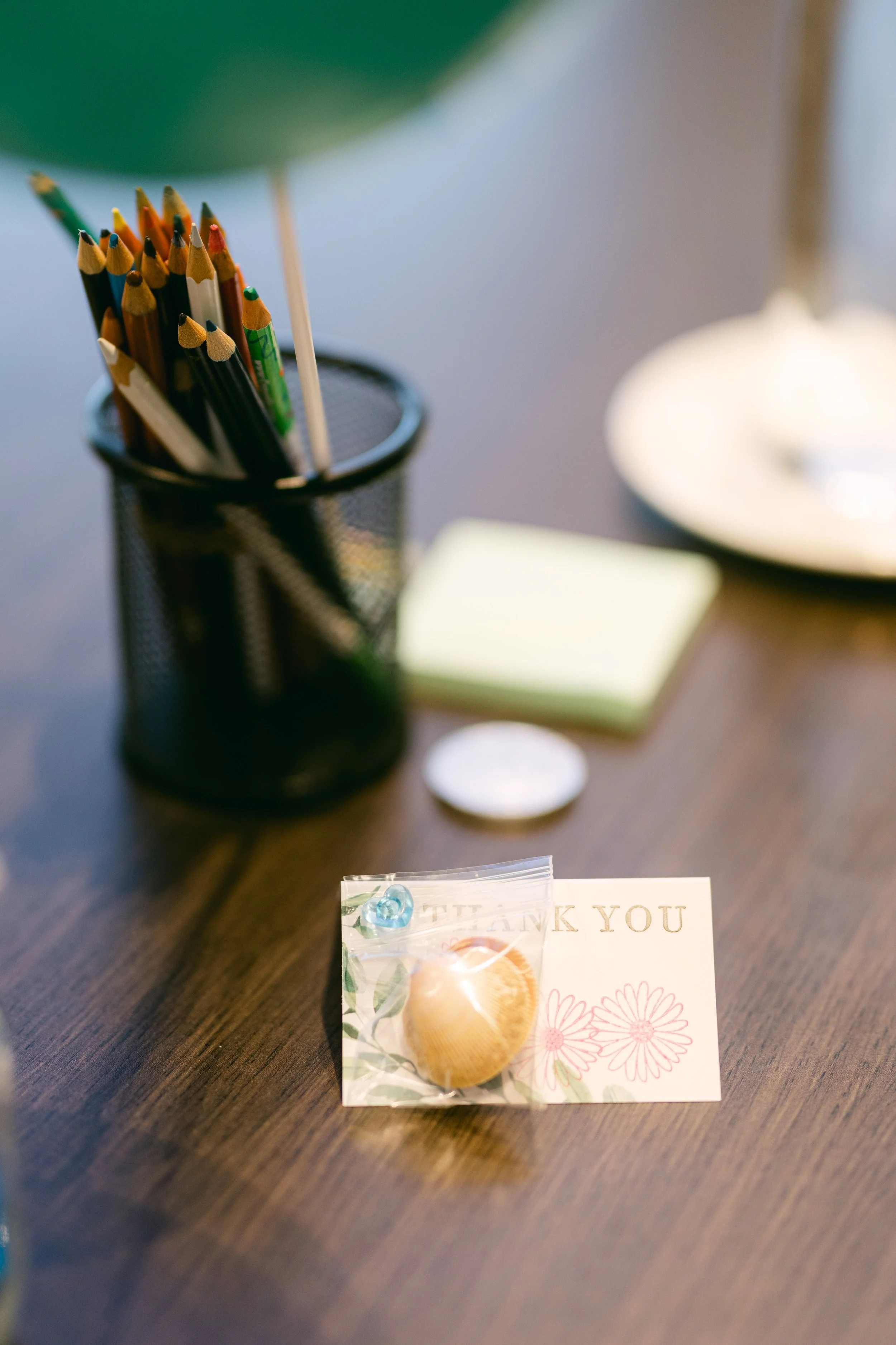Thank you card with a seashell and floral design, placed on a wooden table.