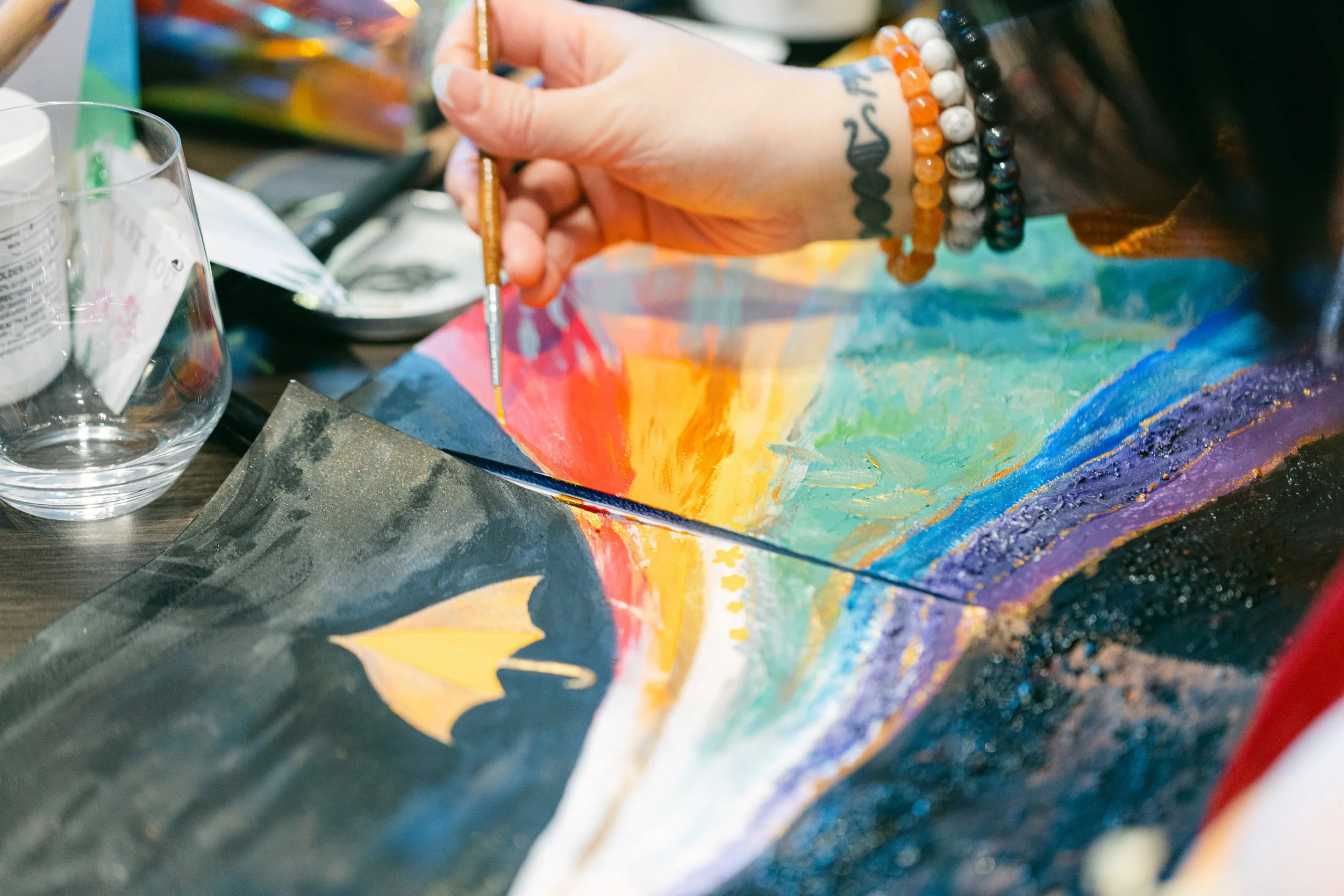 A person painting a colorful landscape with a small airplane in the sky.
