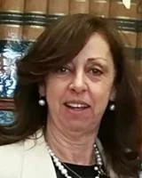 Mulher idosa com cabelo castanho, usando brincos de pérola e colar, sorrindo, fundo de cortina de cortina de iridescente