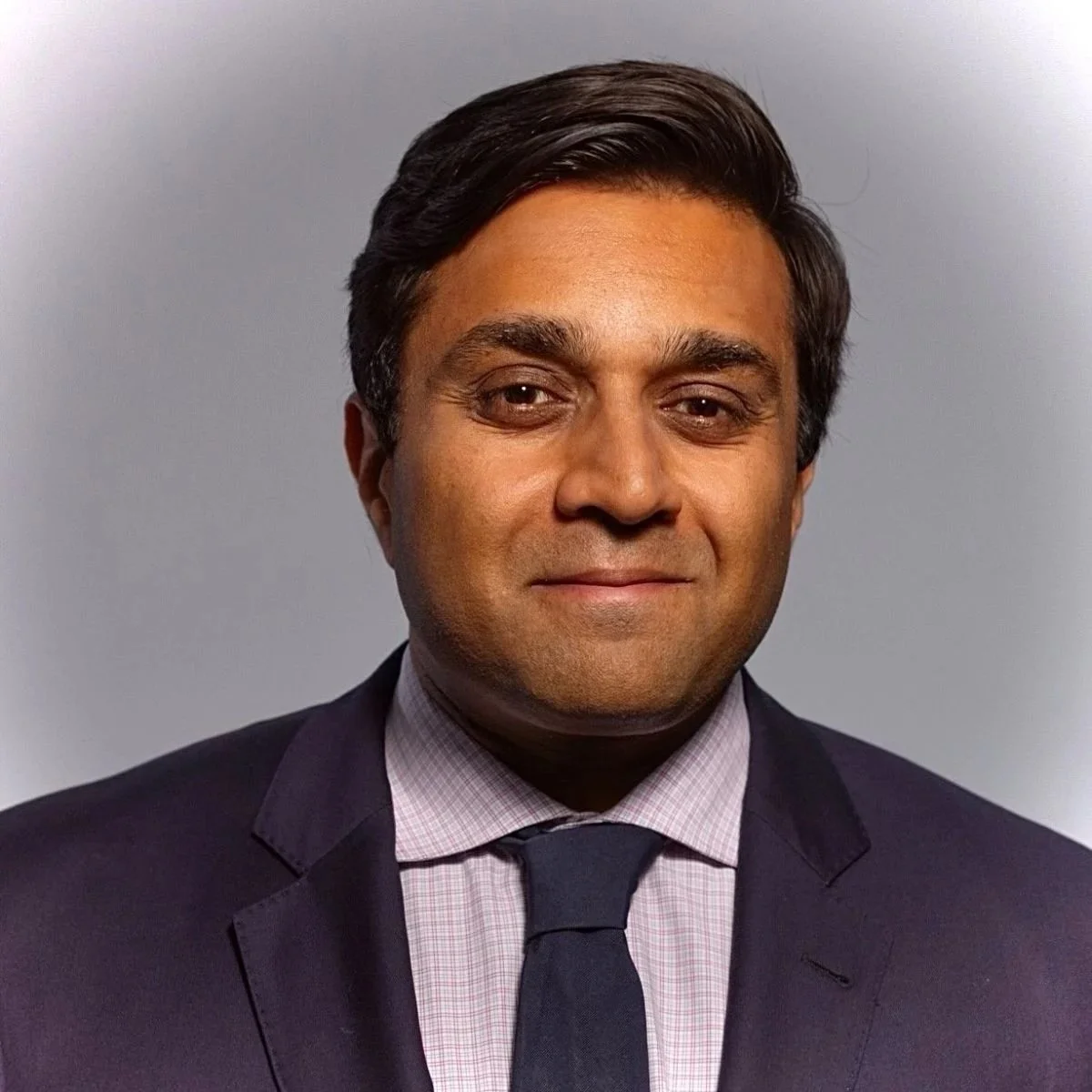 Professional portrait of a man in a suit and tie against a plain background.