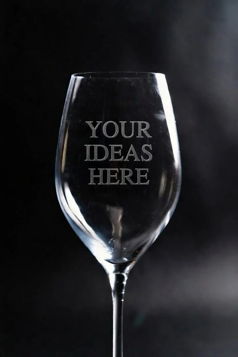 A wine glass with the words "Your Ideas Here" etched onto it, set against a dark background.
