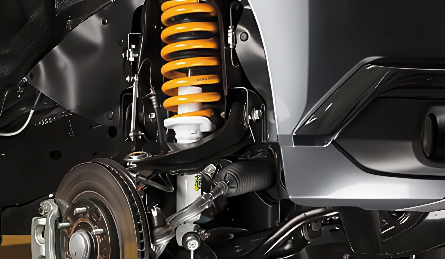 Close-up of a car's suspension system, showing a yellow coil spring, shock absorber, brake rotor, and part of the wheel assembly.