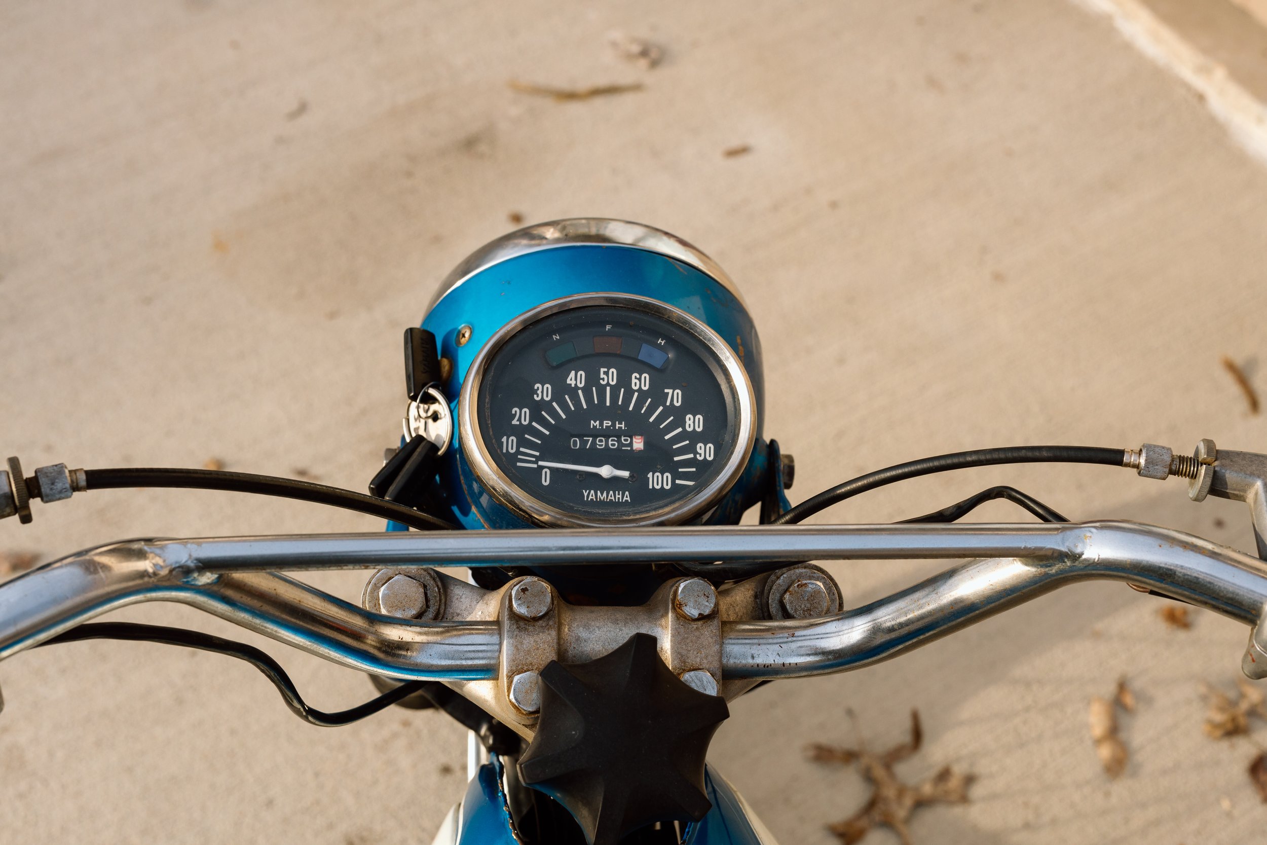 Top view of a blue Yamaha motorcycle's handlebar and speedometer, showing about 7,960 miles.