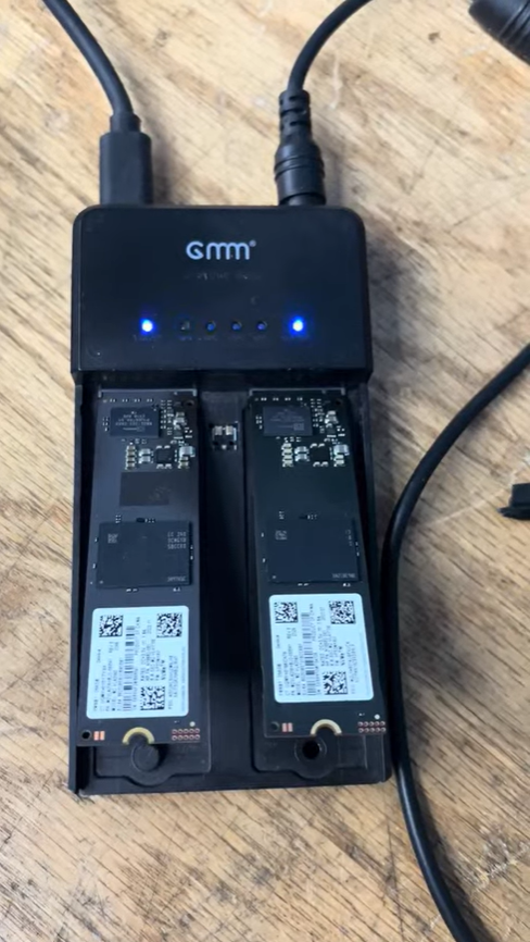 A battery management system with two lithium-ion batteries connected, placed on a wooden surface, with indicator lights and QR code labels visible on the batteries.