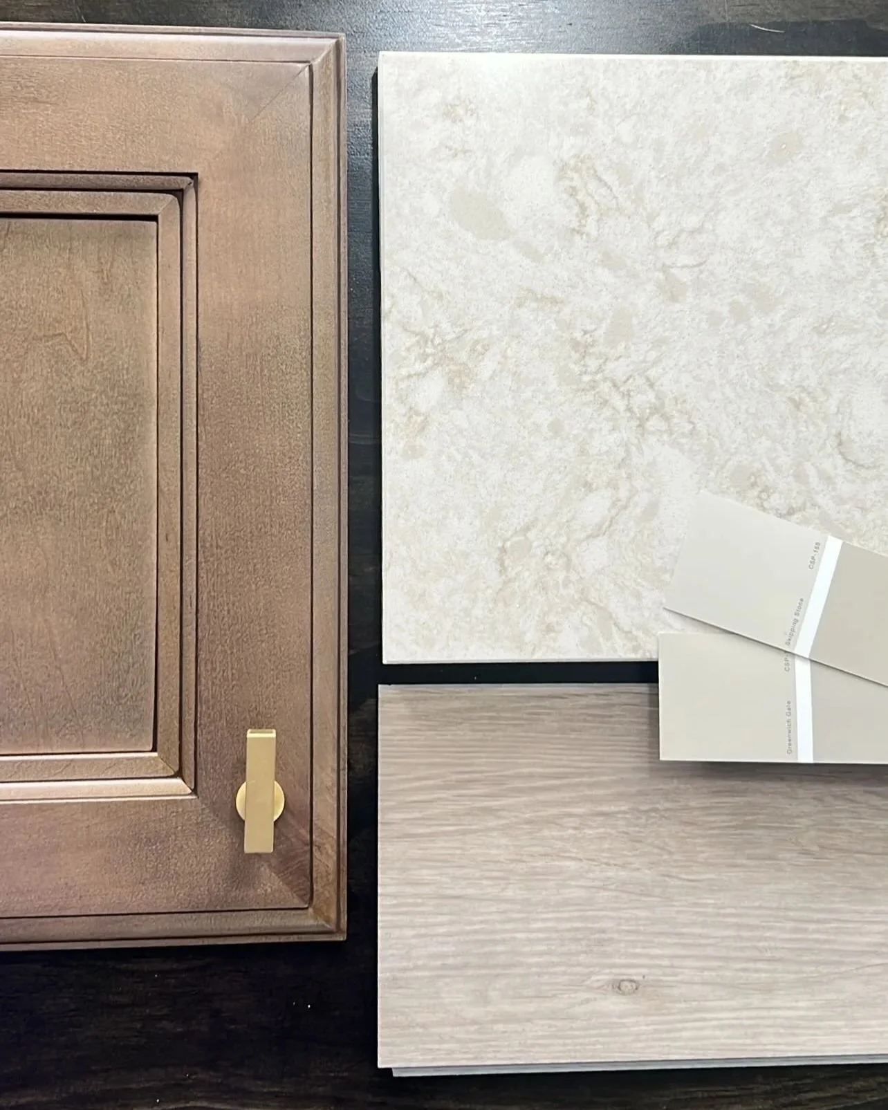 Samples of kitchen cabinet and countertop materials, including a wood cabinet door, a marble countertop sample, and two wood flooring samples.