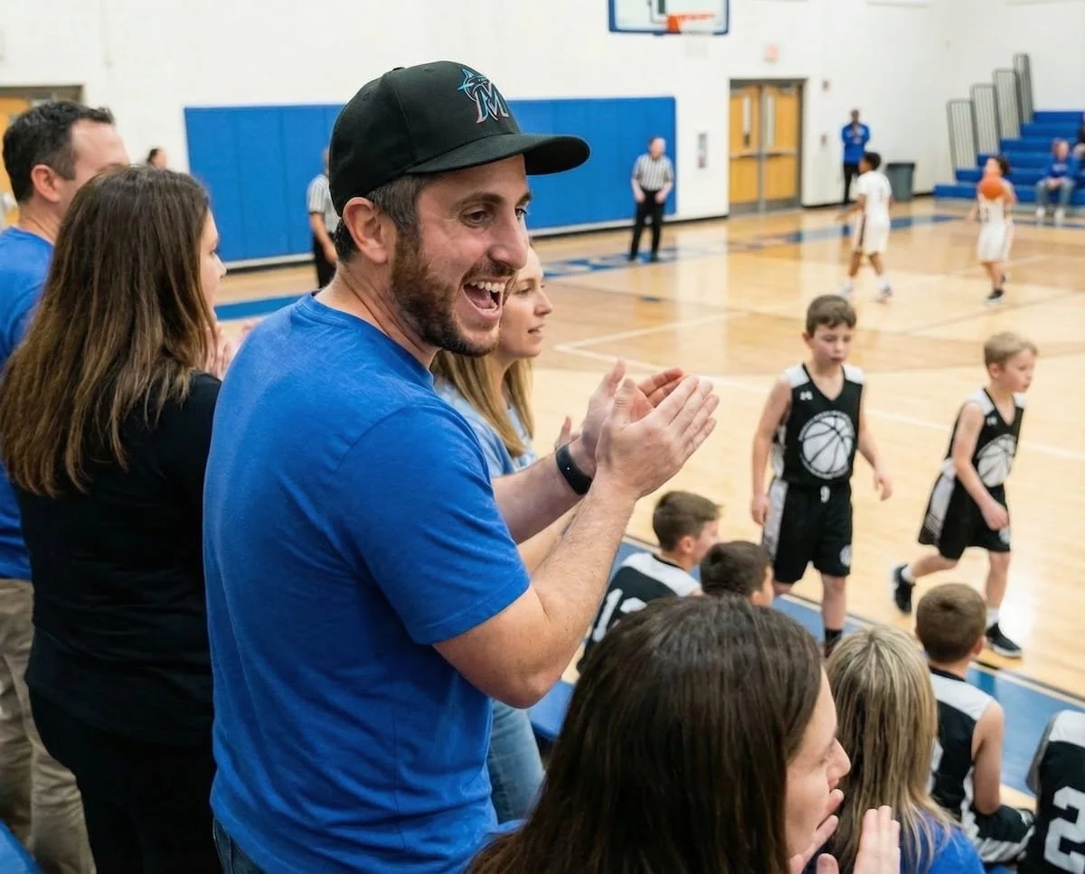 David Feingold, employment attorney and owner of DZ Law, cheering at his son's basketball game in an indoor gymnasium.