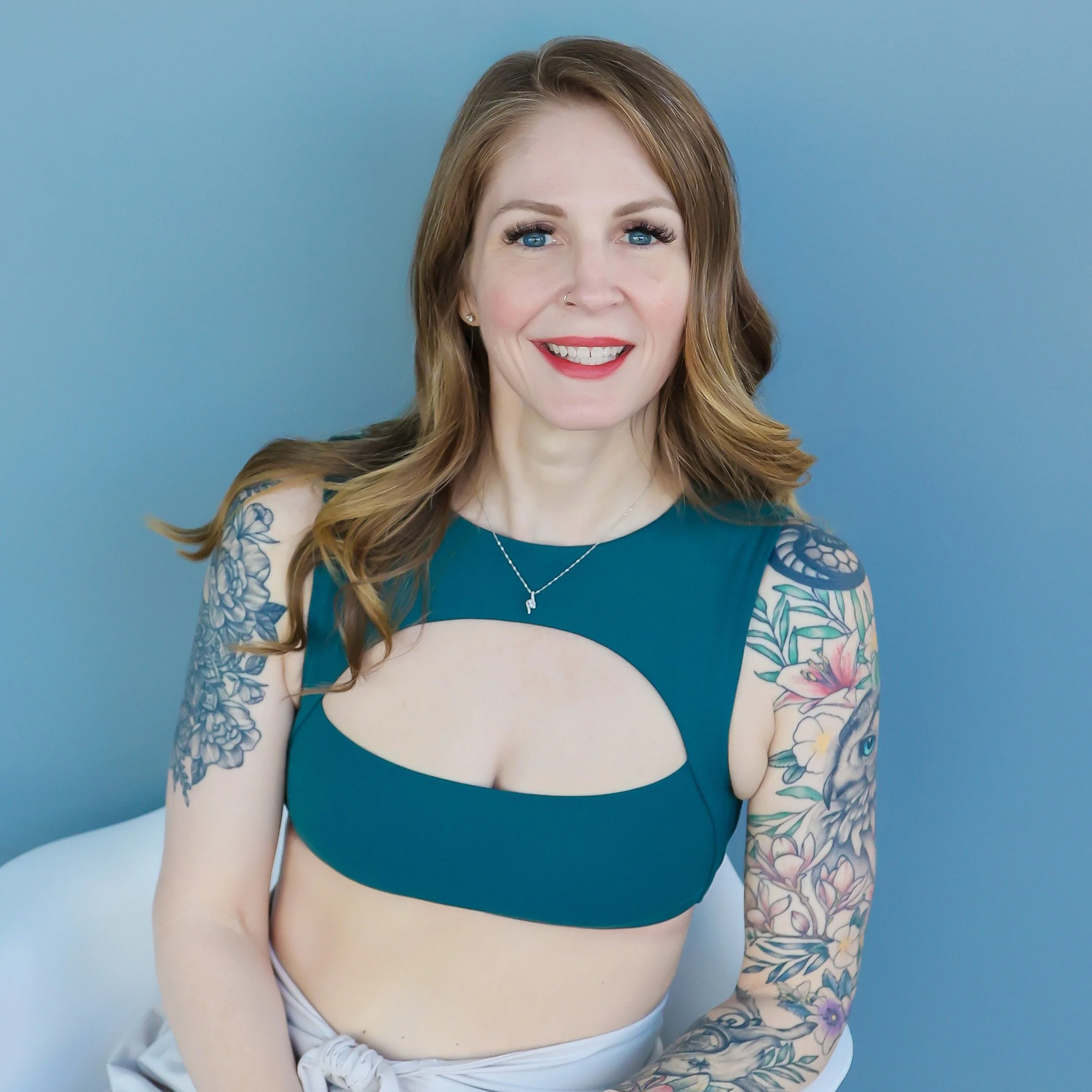 Photo of co-founder Camille Redmann wearing turquoise athletic top sitting in white chair against blue wall
