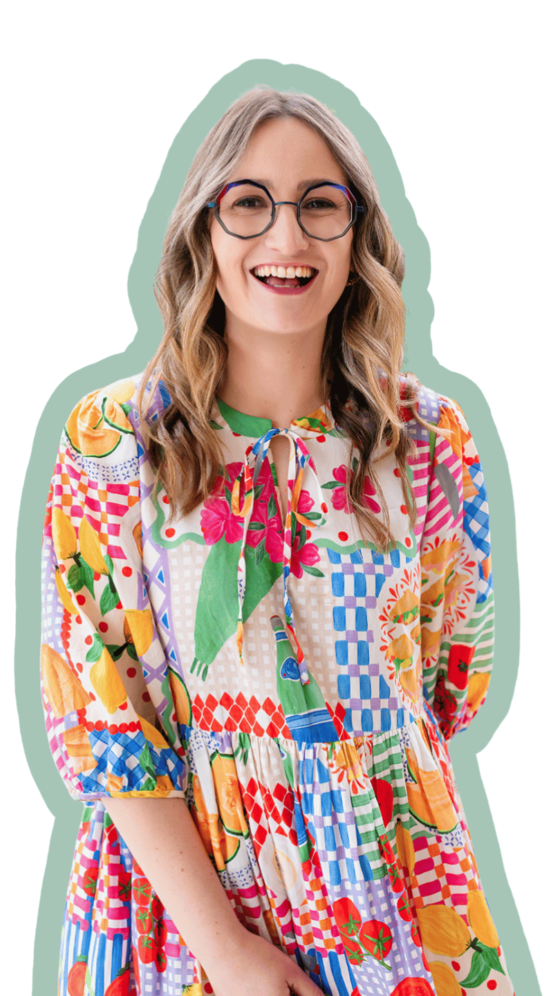 Portrait photo of Liani smiling at the camera. She is wearing a colourful long sleeve dress with a picnic food pattern. There is no background, her body is outlined with a thick green border.