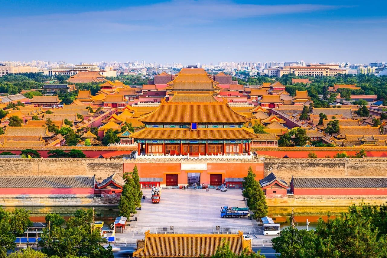 Aerial view of the Forbidden City in Beijing, China with traditional Chinese architecture, yellow roofs, and surrounding cityscape.