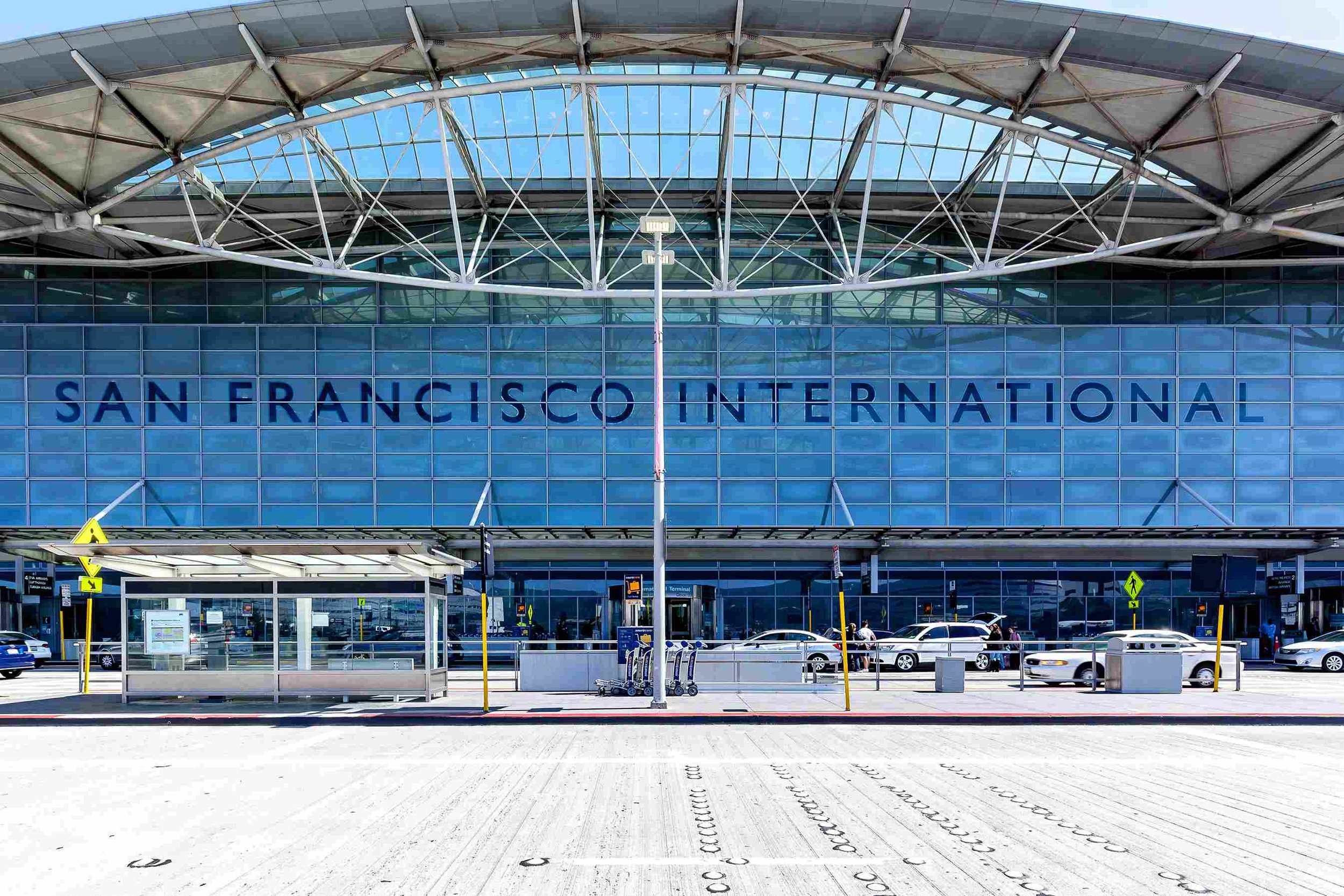 Exterior view of San Francisco International Airport terminal with large glass facade and bold blue lettering.