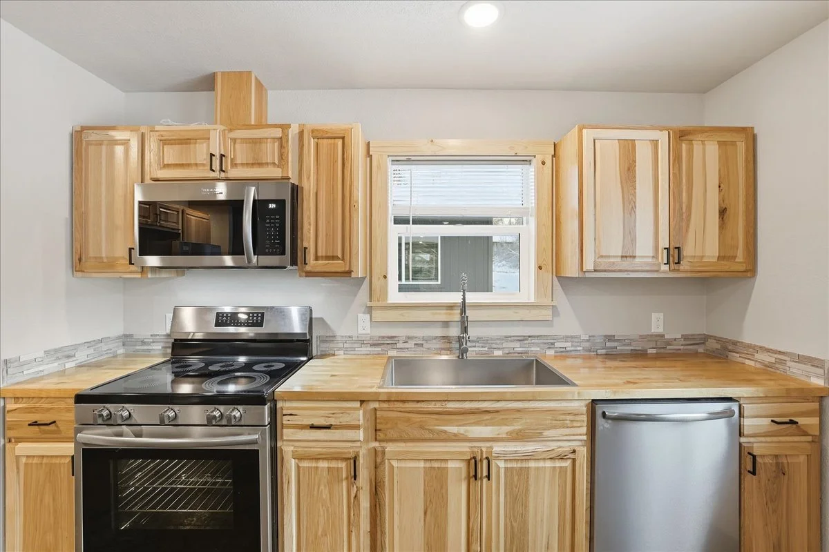 Kitchen with wooden cabinets, a window above the sink, stainless steel appliances including a microwave, oven, and dishwasher.