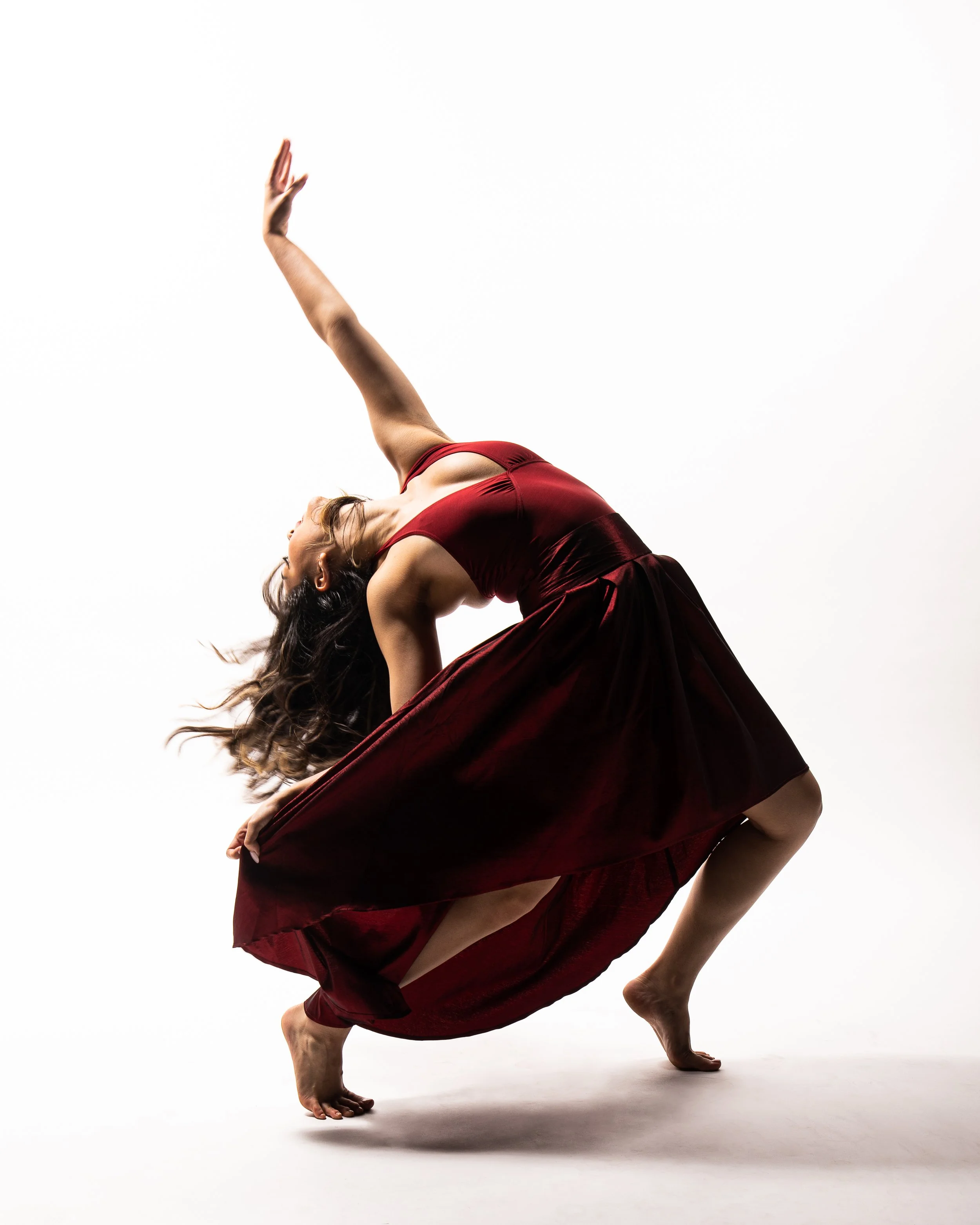 Woman in a red dress performing a dance pose on a white background.