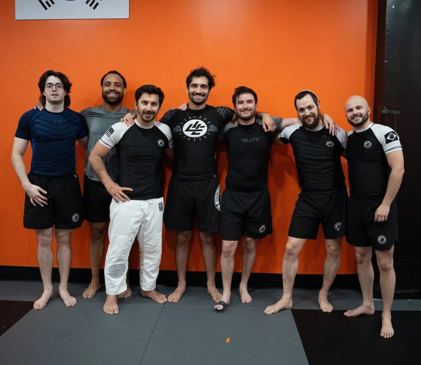 Picture of jiu jitsu class members huddled together and smiling for the camera after jiu jitsu class.