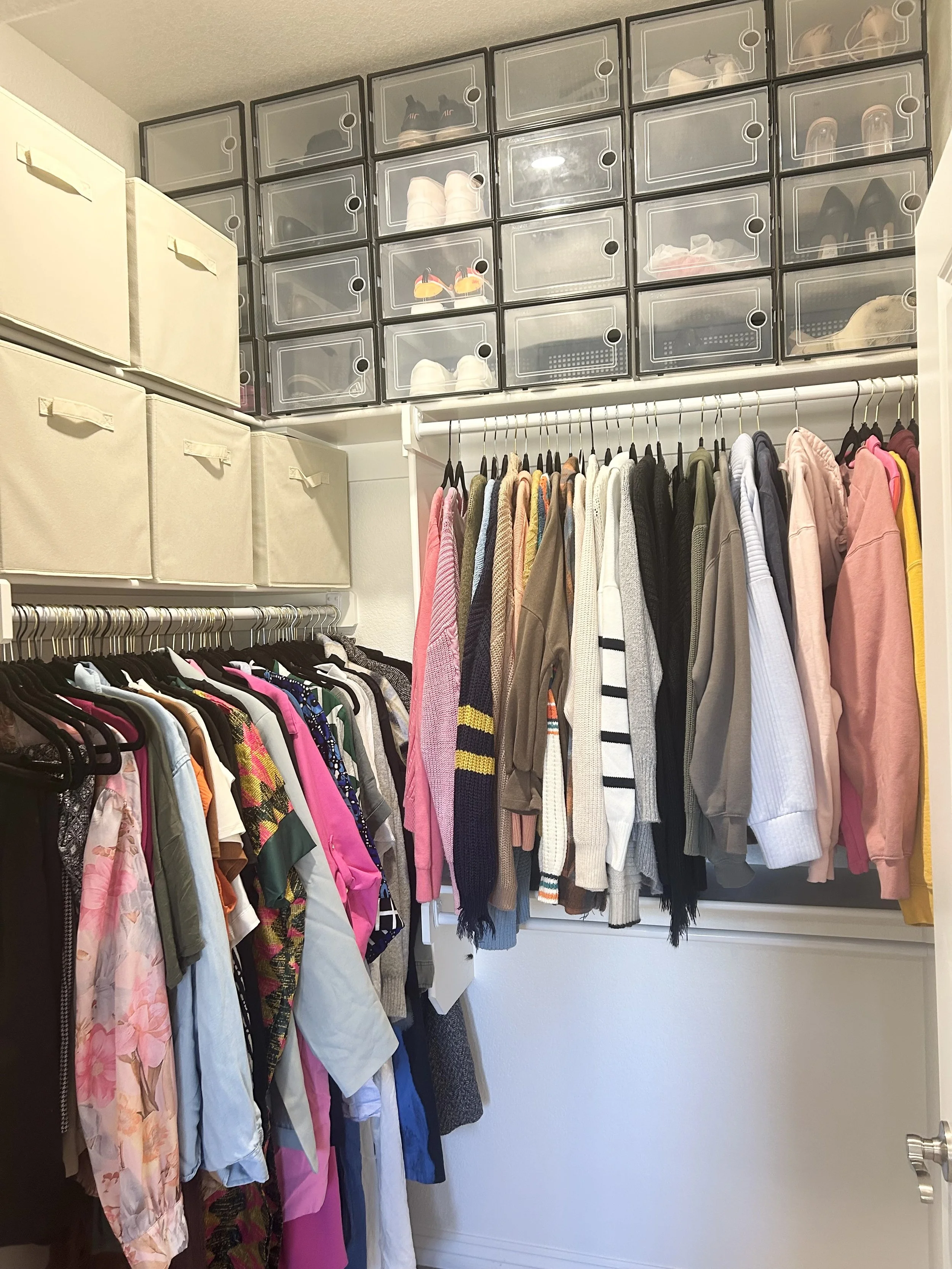 Closet with organized clothing and shoe storage, including a wall of transparent bins and shelves with shoes.