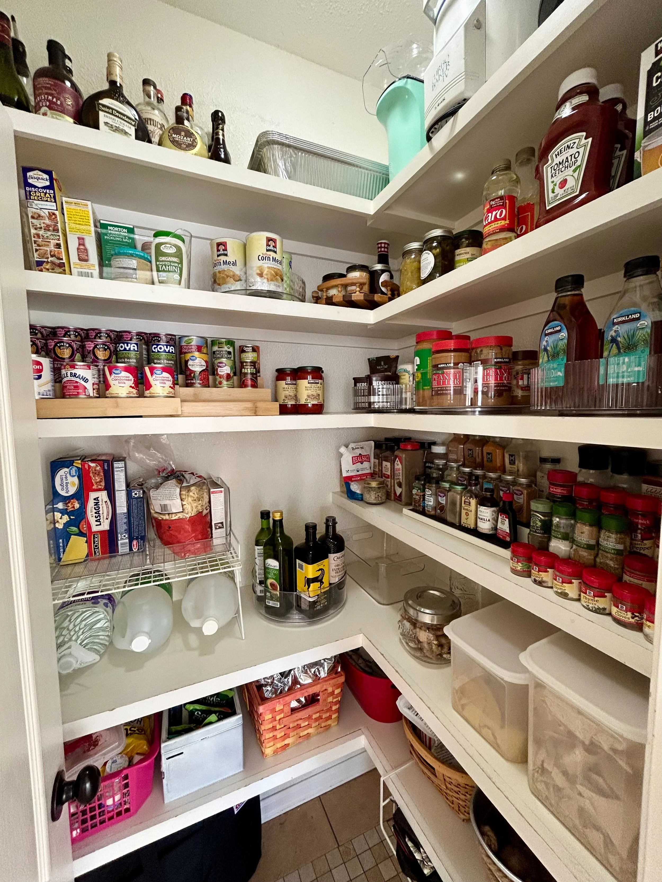 Pantry closet filled with various jars, bottles, cans, and containers of food items, spices, and condiments, organized on multiple shelves.