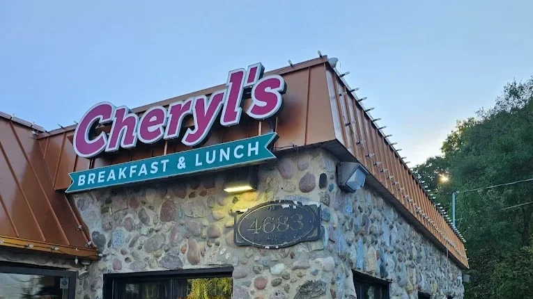 Exterior of Cheryl's restaurant with a sign reading 'Cheryl's Breakfast & Lunch' on a stone building with a metal roof.
