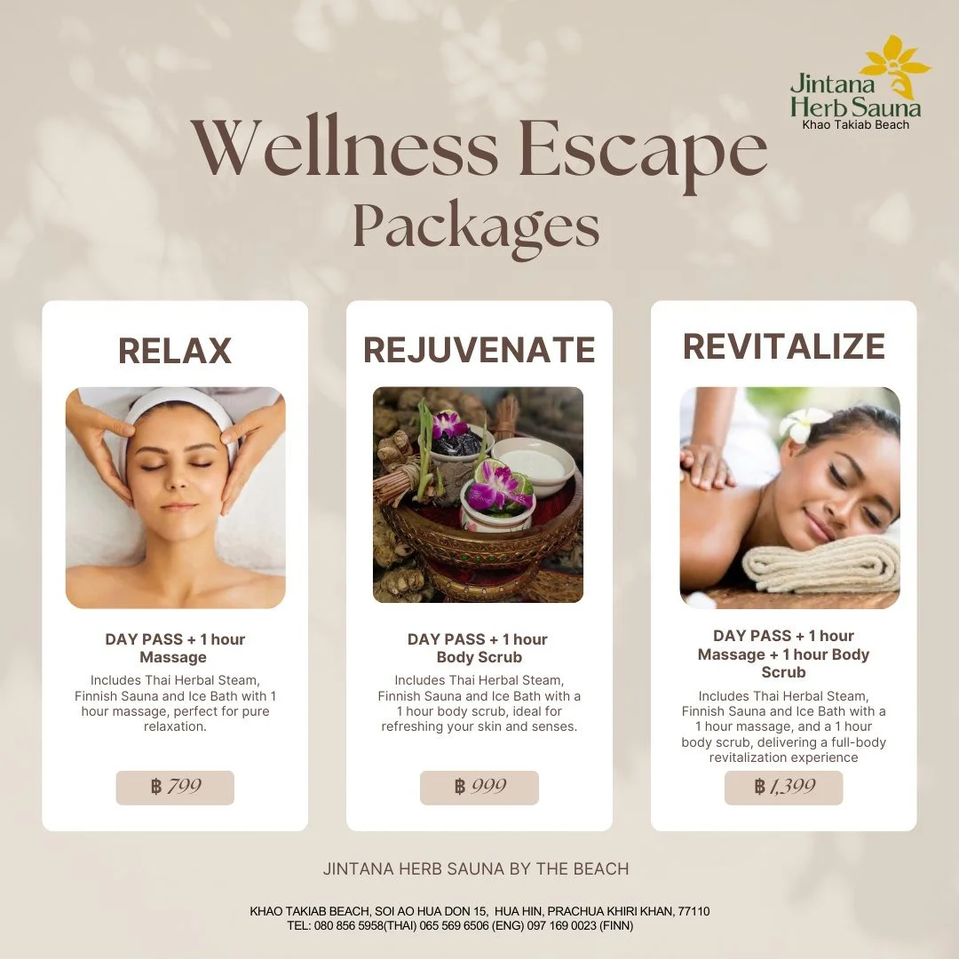 A massage or spa treatment room with three beds, each with folded towels and black stones on top, behind a table with folded towels underneath. Two fans are mounted on the ceiling, and a small green clock is on the wall.