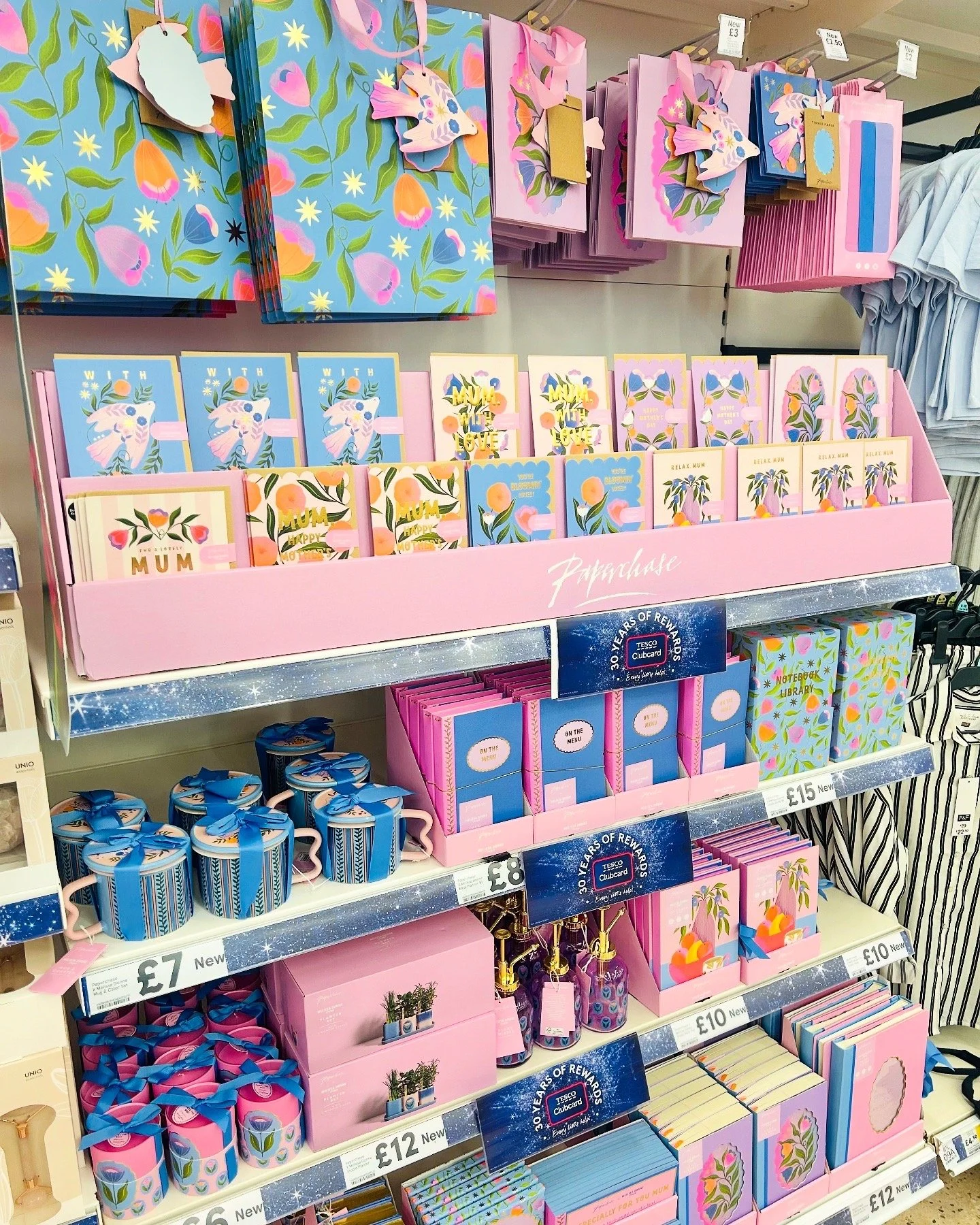 Shelf display of Mother's Day and spring-themed greeting cards, gift wrap, and small gift accessories in pastel colors and floral patterns.