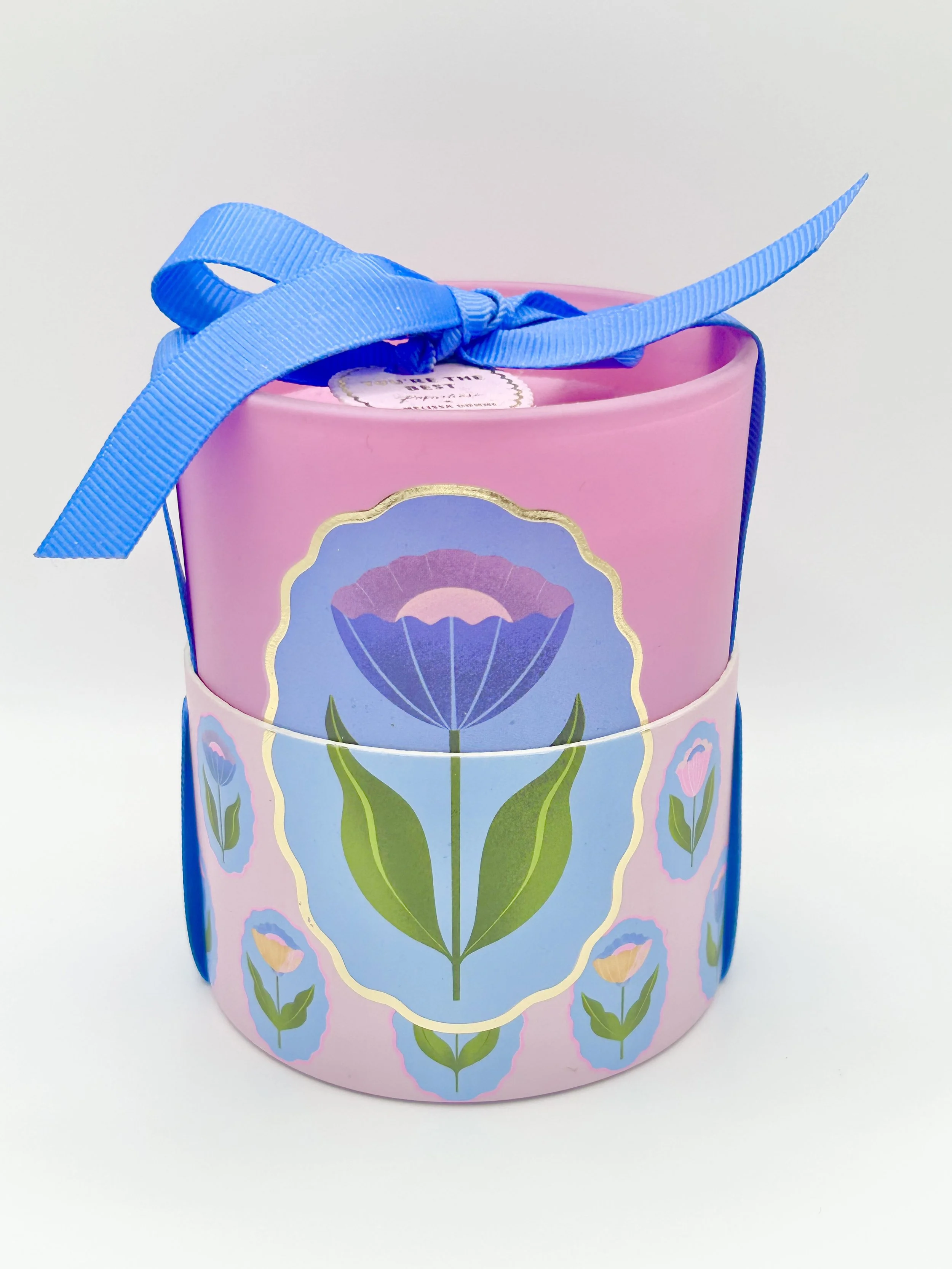 A pink cylindrical container with a blue floral pattern and a blue ribbon bow on top.