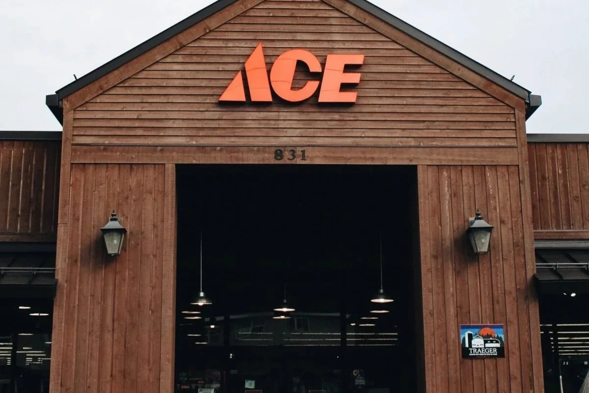 Front of an ACE hardware store made of wood, with the large red ACE logo sign at the top.