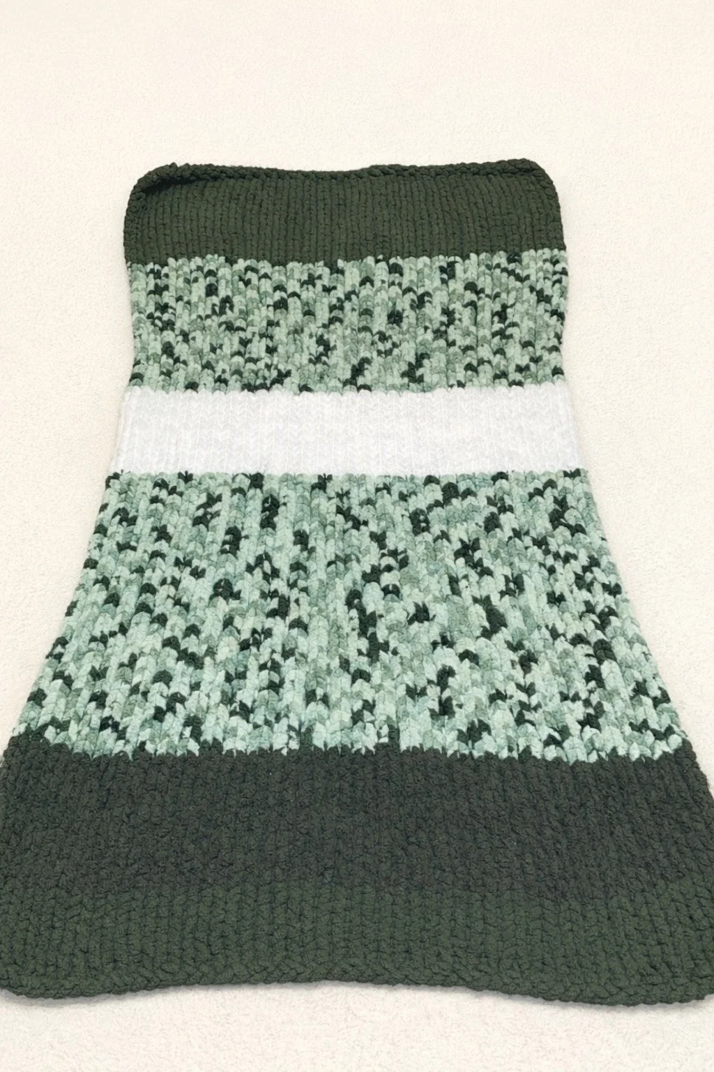 Colorful knit sock with dark green, white, and light blue patterns.