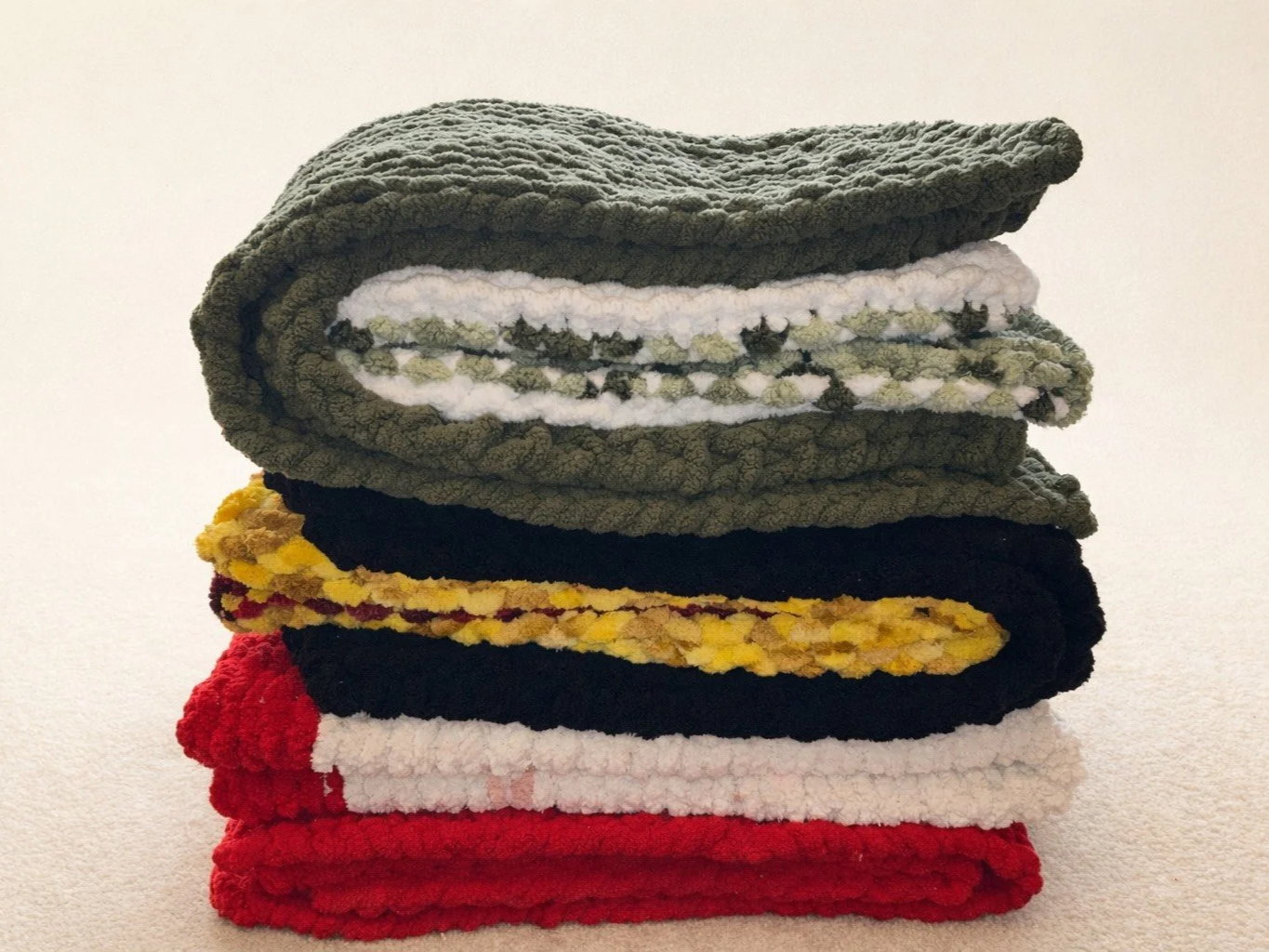 A neatly folded stack of colorful towels placed on a light-colored surface.