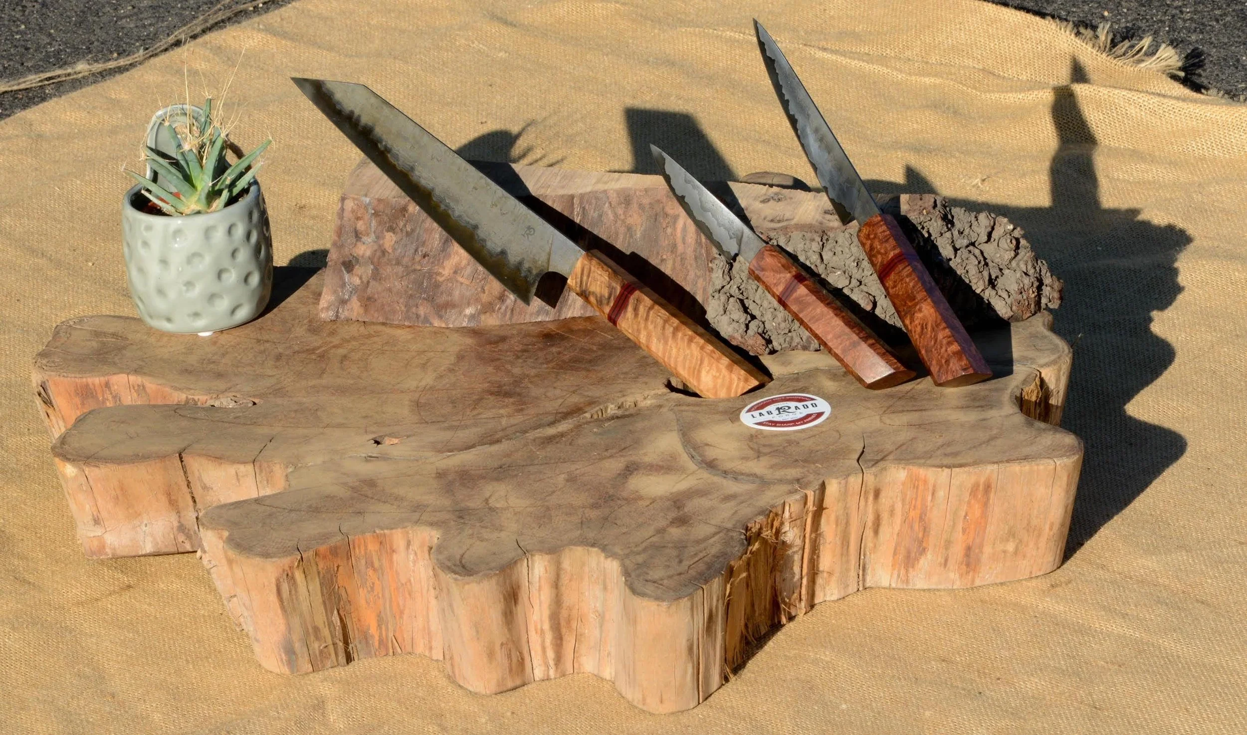 A custom set wrought iron sanmai with 1095 core. Handles are locally sourced Oak and Redwood burl with red and black micarta spacers (2023) 